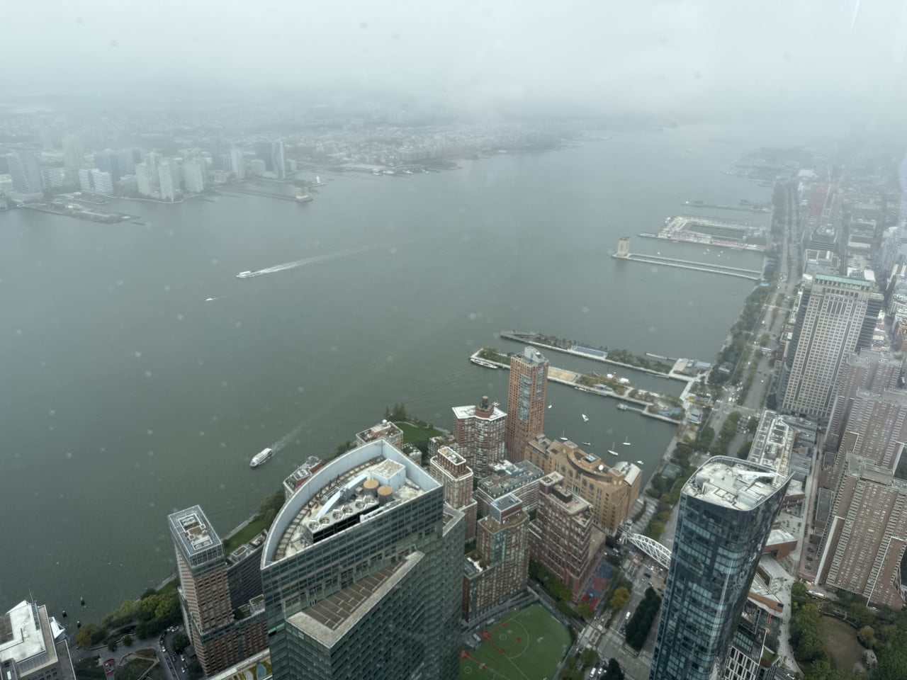 Výhled na Manhattan a řeku Hudson z výšky, v mlze s loděmi na vodě.