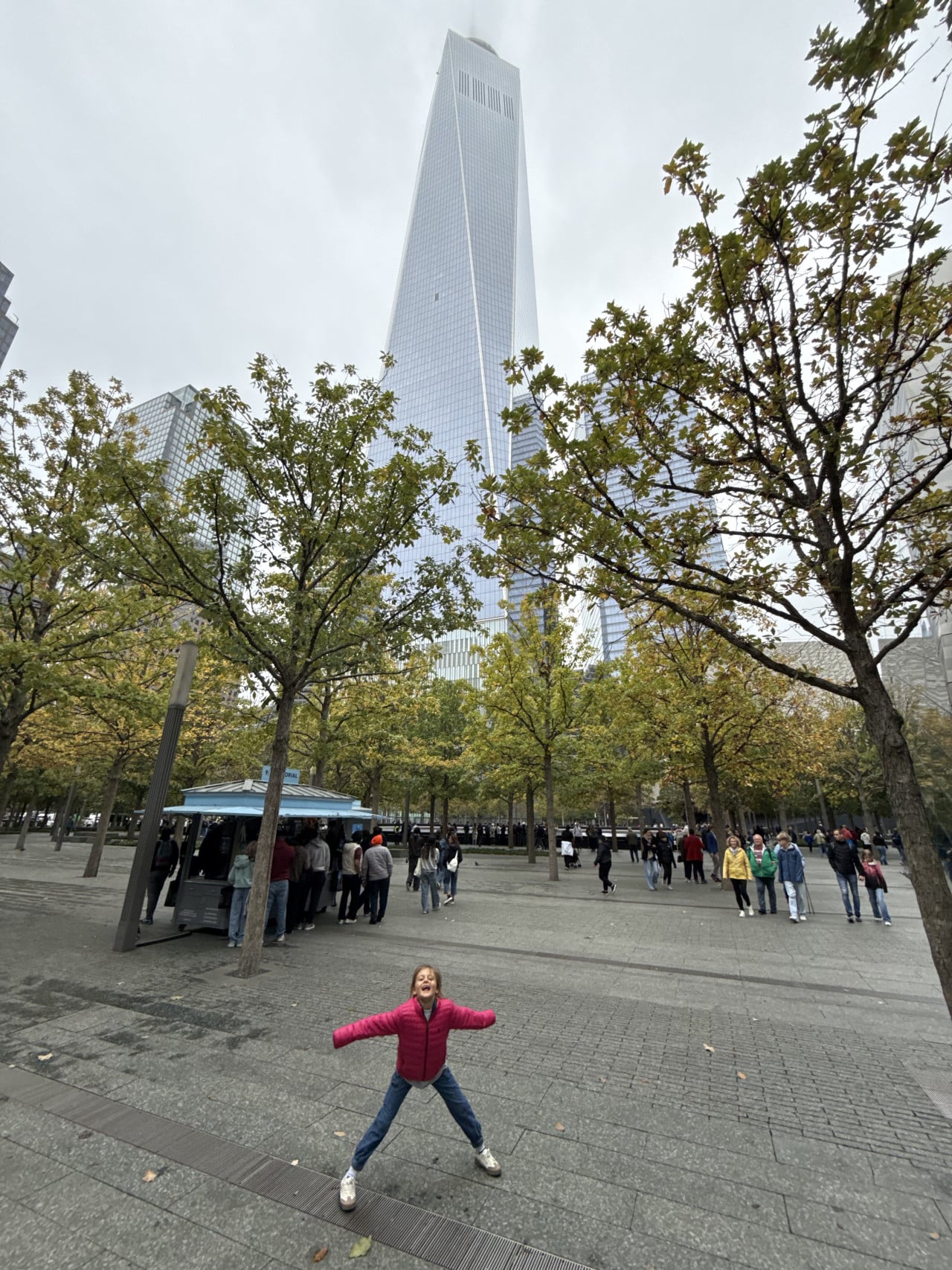 One World Trade Center nad 9/11 Memorial s dívkou v popředí.