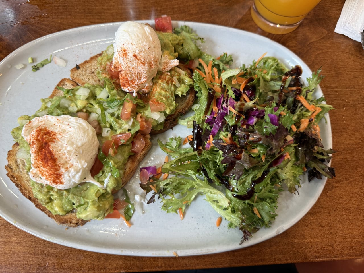 Avokádový toast s vejci a salátem na talíři v newyorské kavárně.