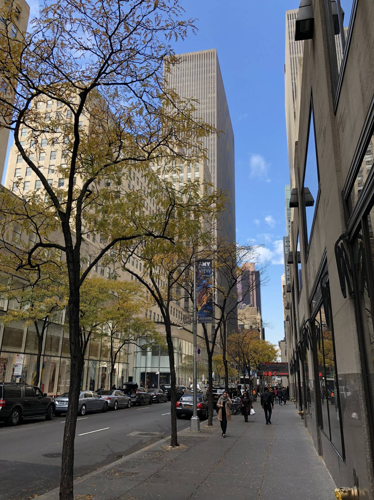 Ulice v New Yorku s mrakodrapy, stromy a červeným nápisem NBC Studios