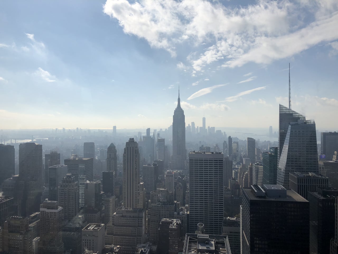 Panorama Manhattanu s Empire State Building a mrakodrapy pod modrou oblohou.