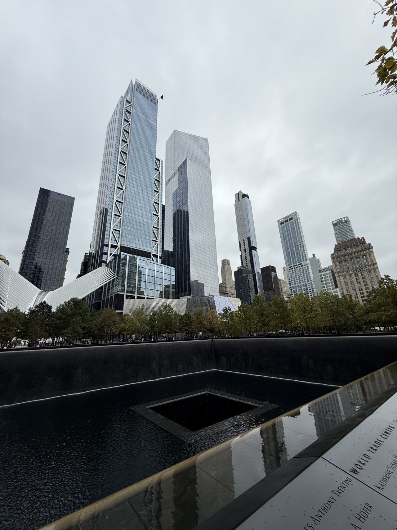 One World Trade Center nad 9/11 Memorial s odrazovými bazény a nápisy obětí