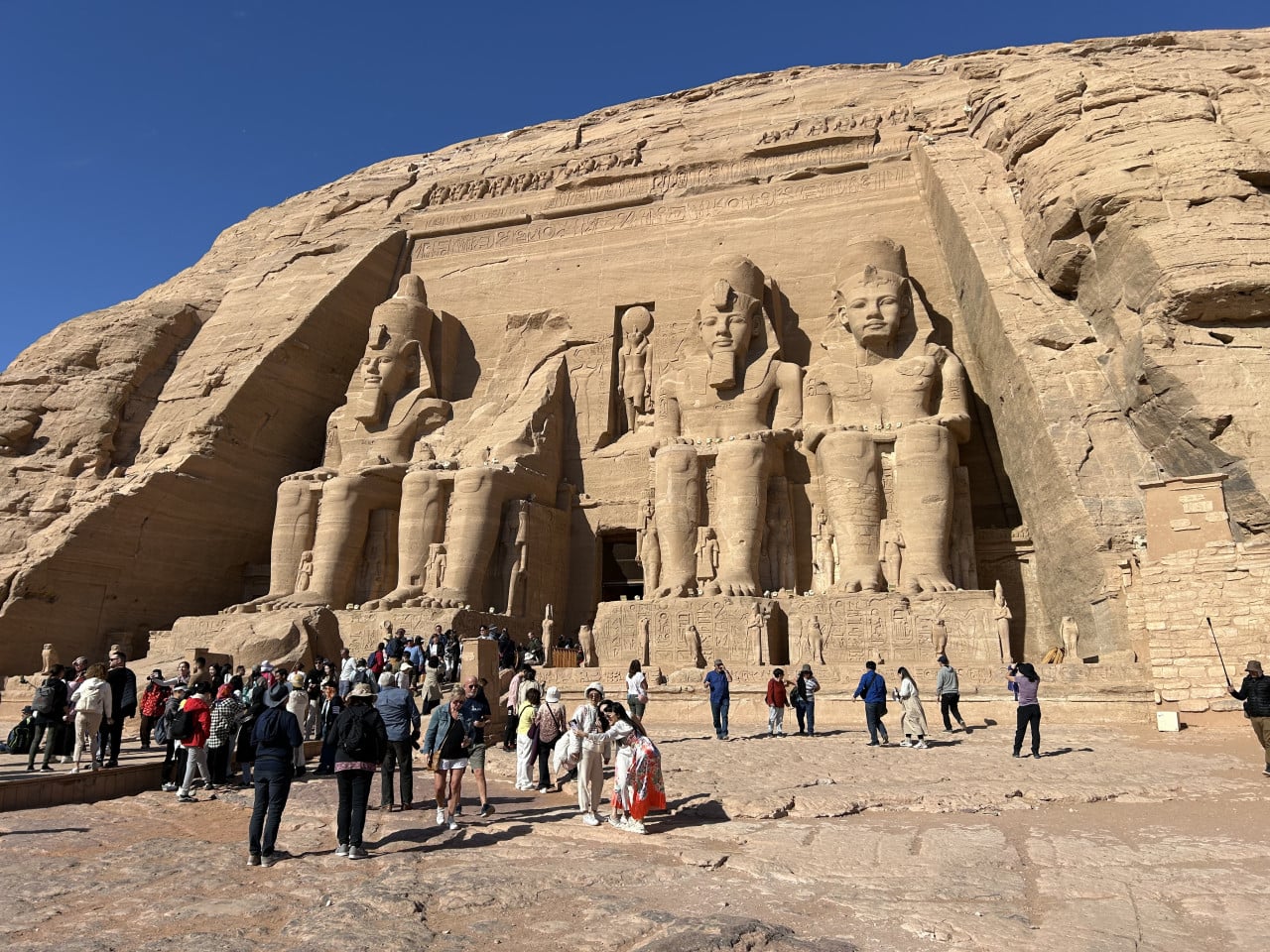 Chrám Abu Simbel s obřími sochami a turisty před průčelím