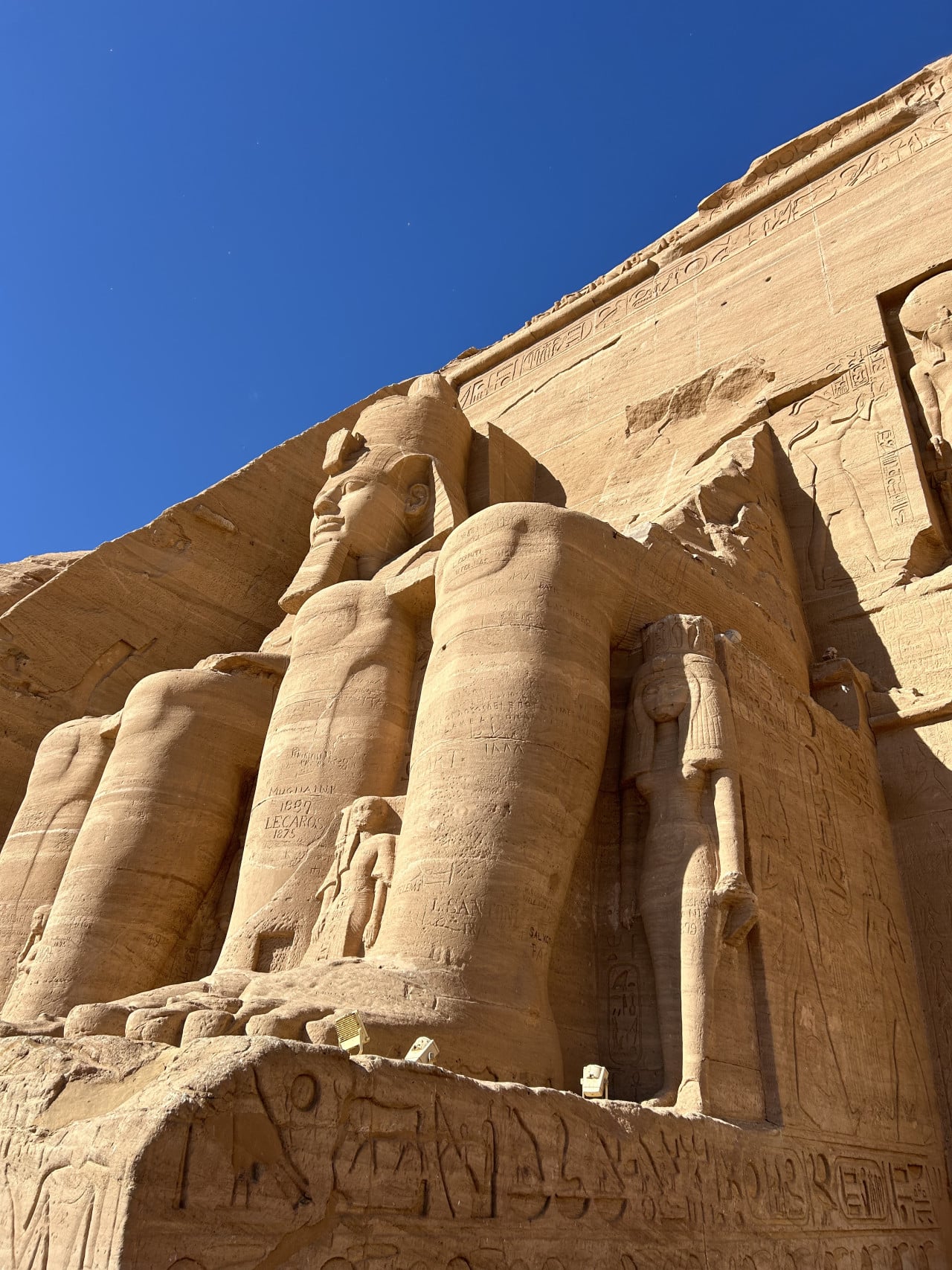 Kolossální sochy a reliéfy chrámu Abu Simbel pod modrou oblohou