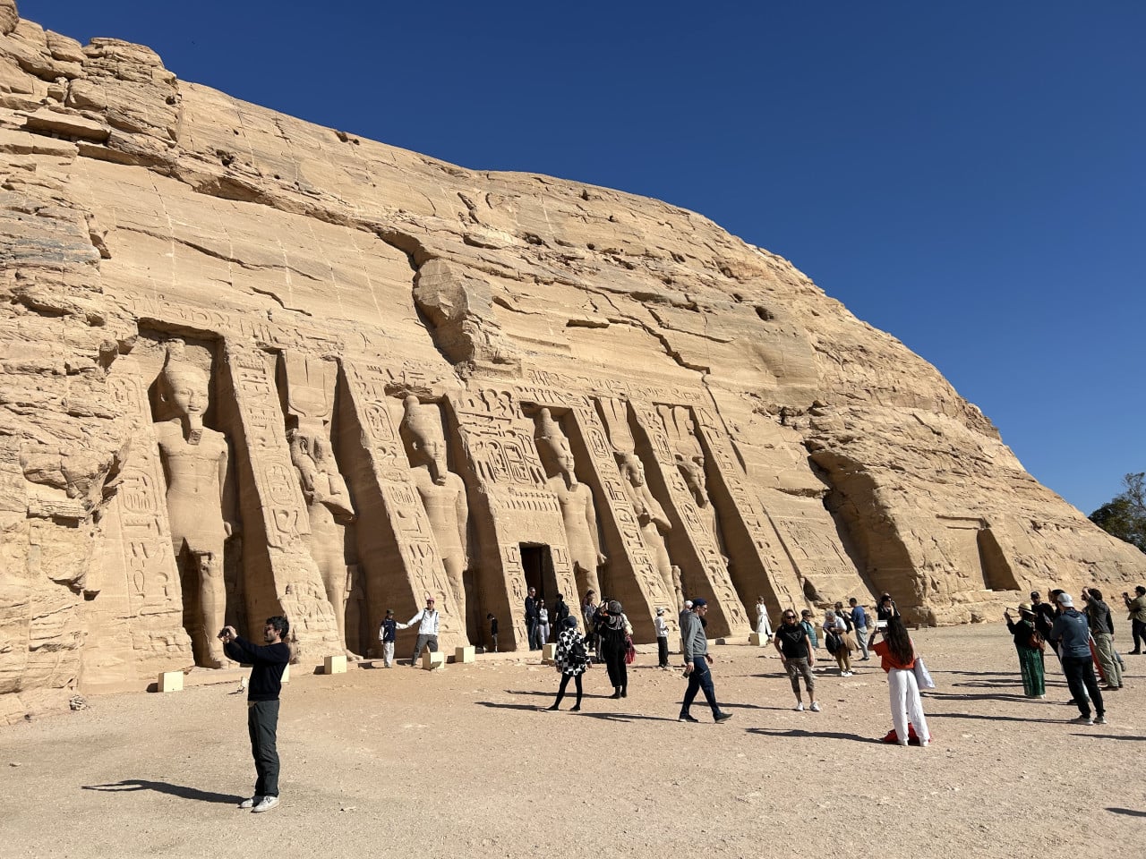 Chrám Abu Simbel vytesaný ve skále, turisté před monumentální fasádou.