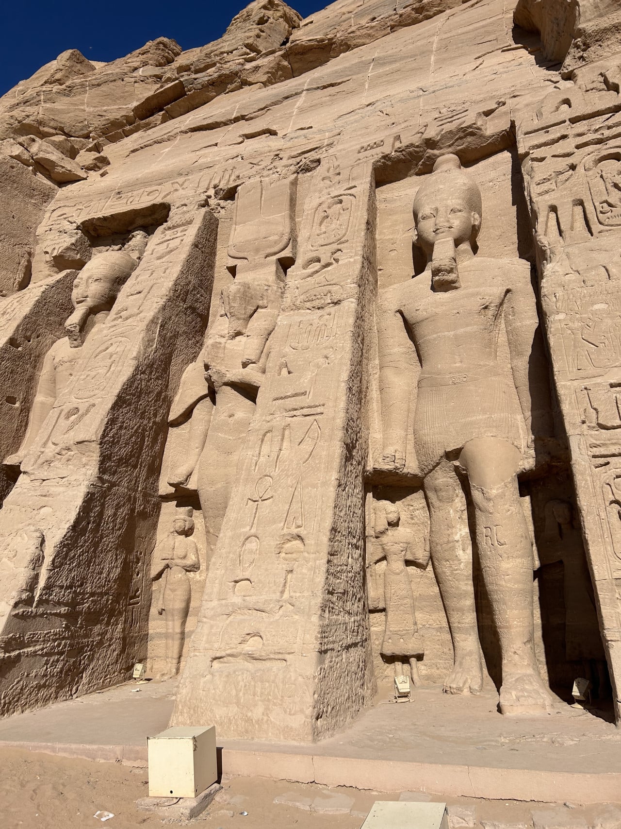 Faraonské sochy a hieroglyfy vytesané do skalní stěny chrámu Abu Simbel.