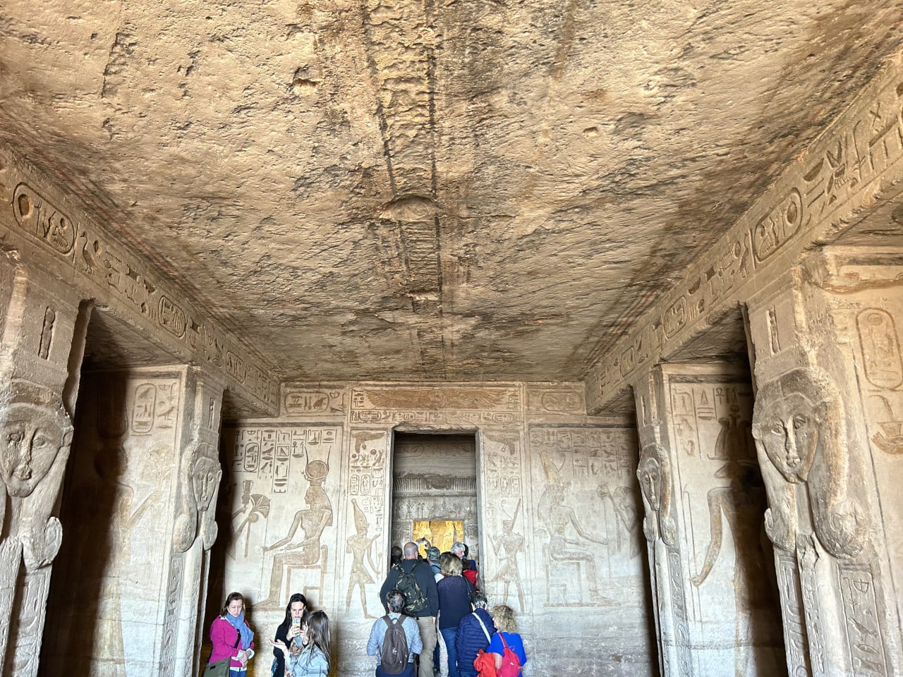 Vnitřek skalního chrámu Abu Simbel s reliéfy a turisty u vstupu
