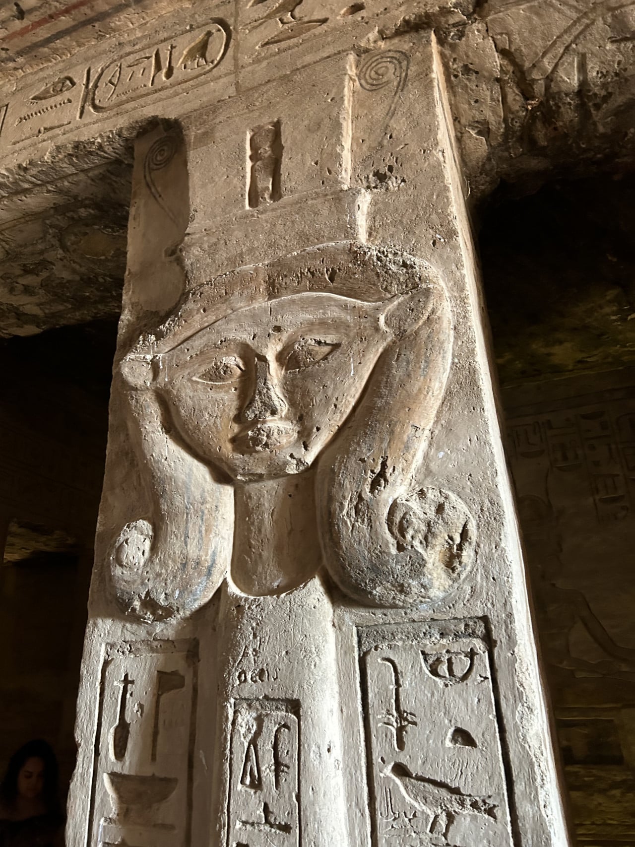 Reliéfní sloup s egyptskými hieroglyfy a tváří bohyně uvnitř chrámu Abu Simbel