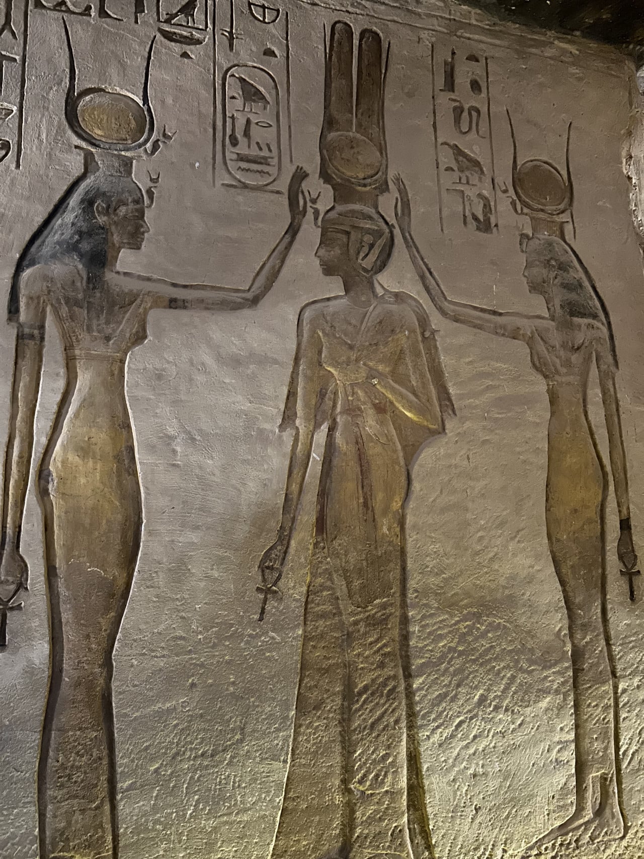Reliéf tří egyptských postav s hieroglyfy na kamenné stěně