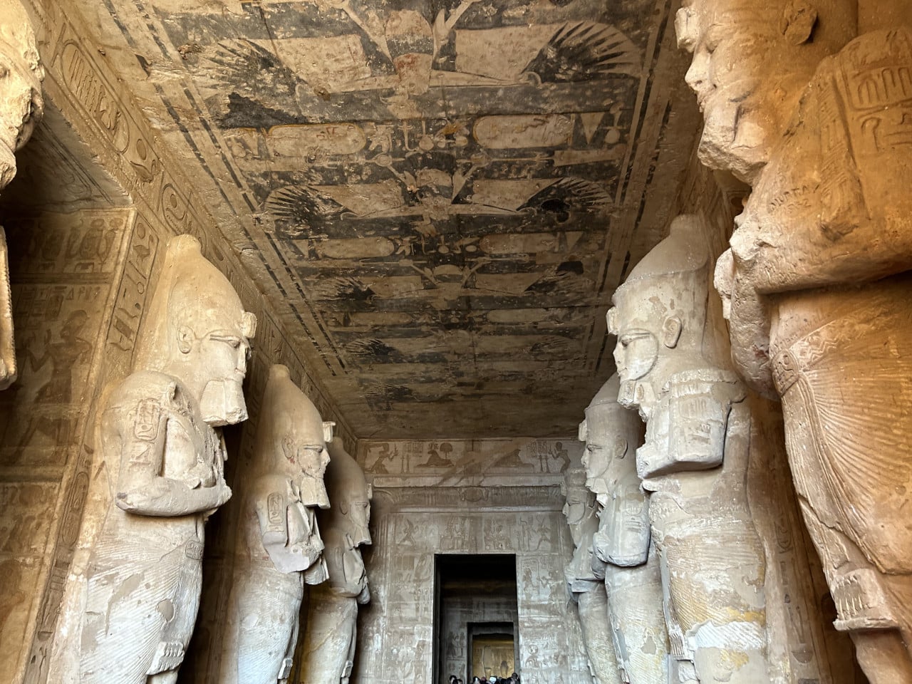 Interiér chrámu Abu Simbel s obřími sochami faraonů a zdobeným stropem