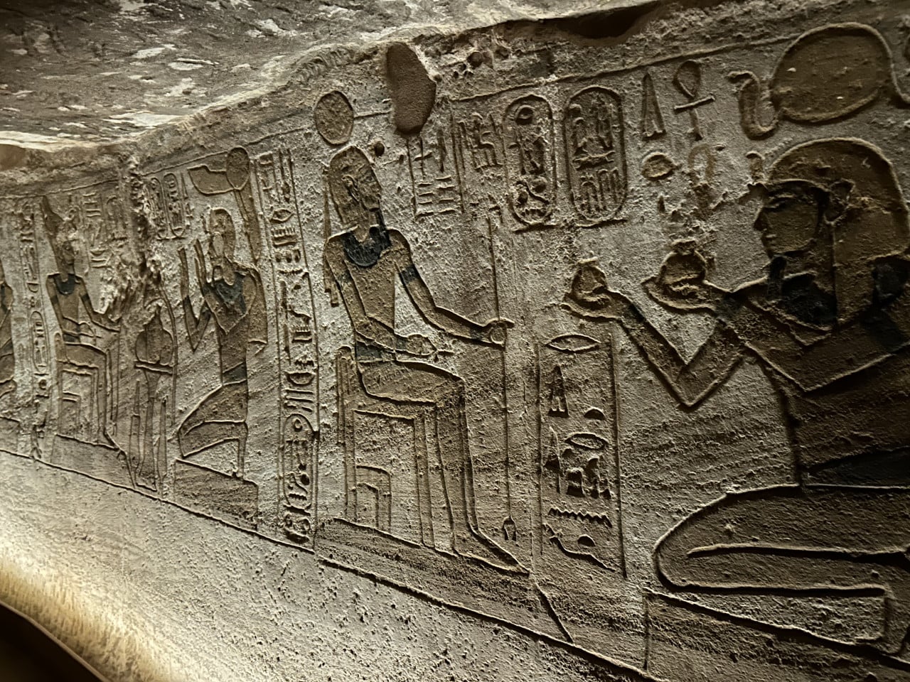Reliéf s egyptskými hieroglyfy a postavami na kamenné stěně v Abu Simbelu