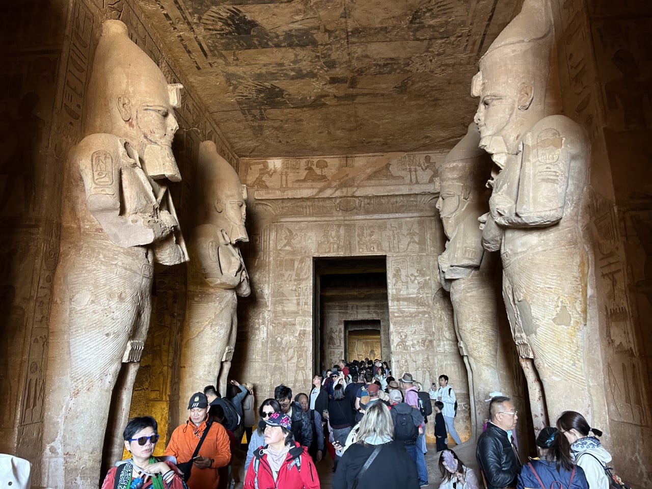 Interiér chrámu Abu Simbel s obřími sochami a turistickým davem