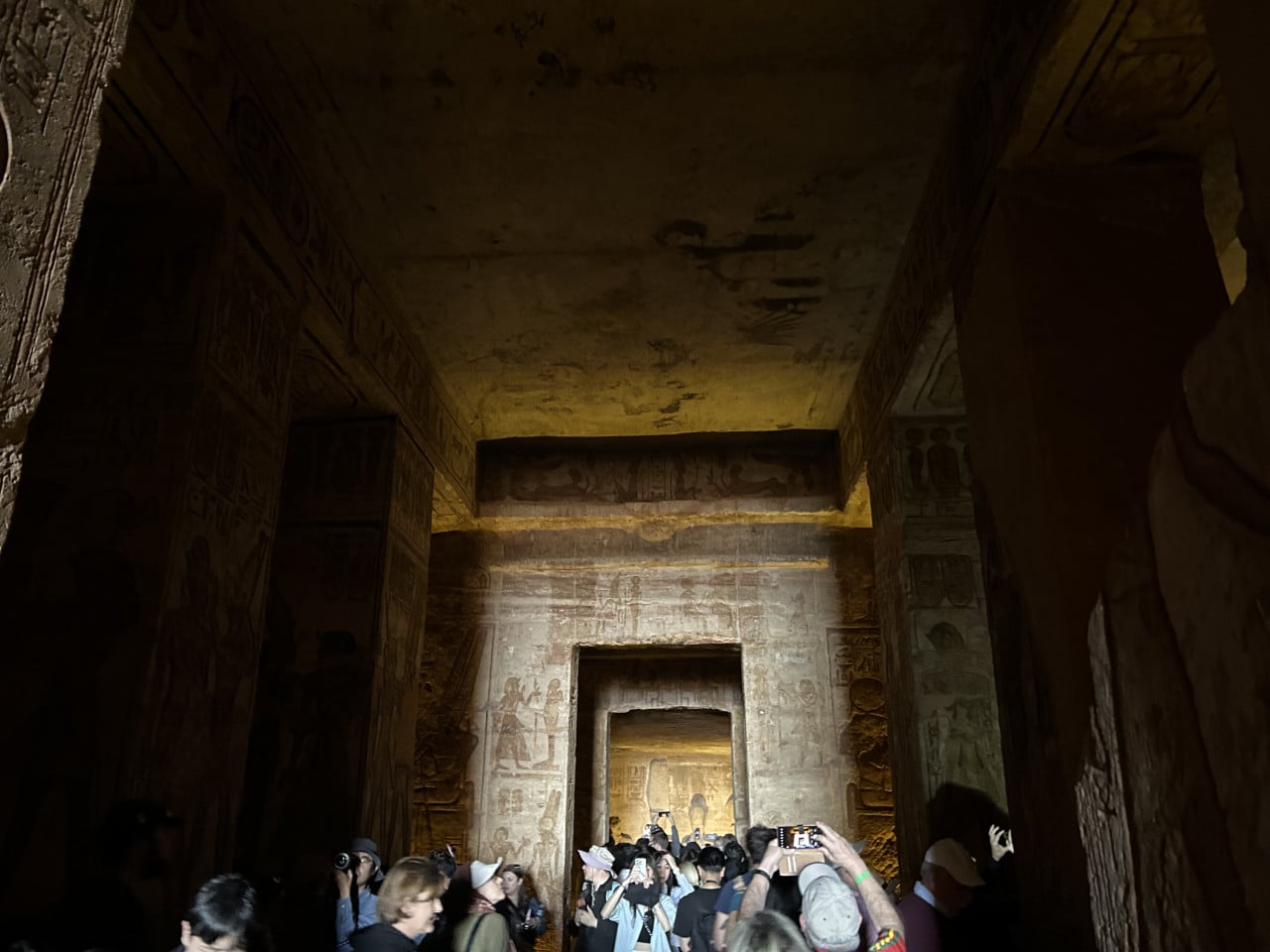 Turisté fotografují vyzdobený interiér chrámu Abu Simbel v tlumeném světle
