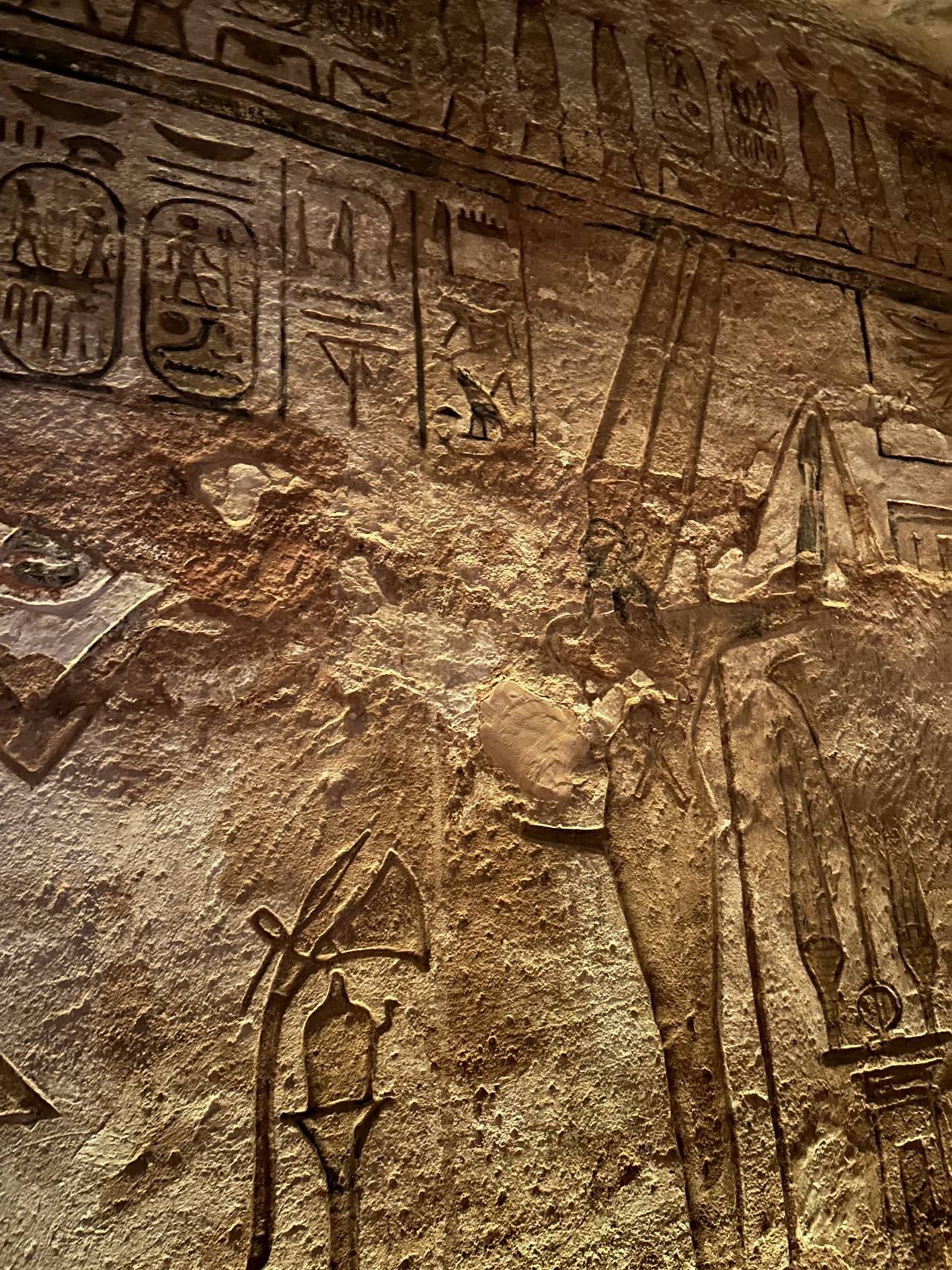 Detail staroegyptských reliéfů a hieroglyfů na kamenné stěně chrámu