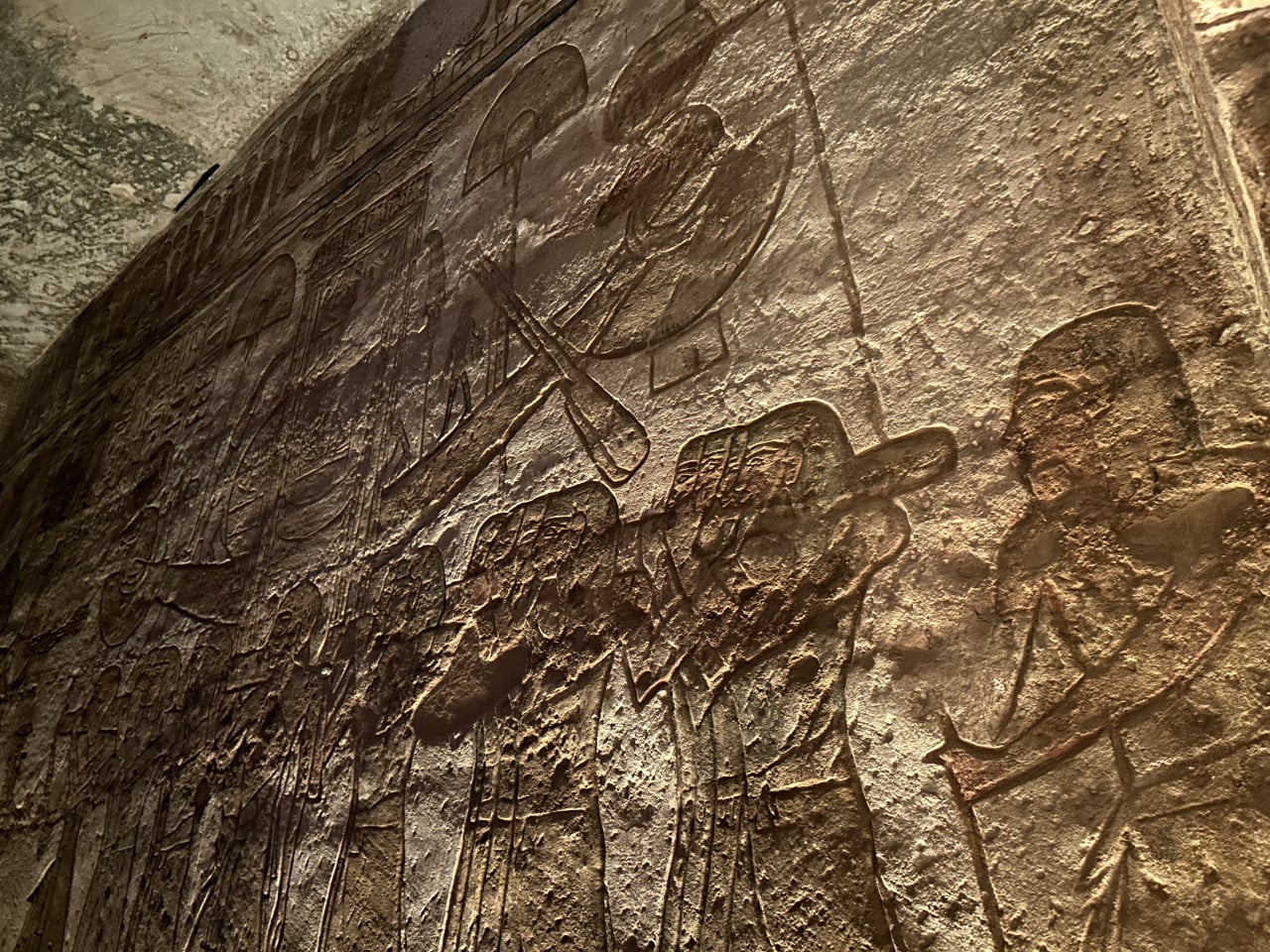Vytesaný reliéf s egyptskými postavami a hieroglyfy na kamenné stěně