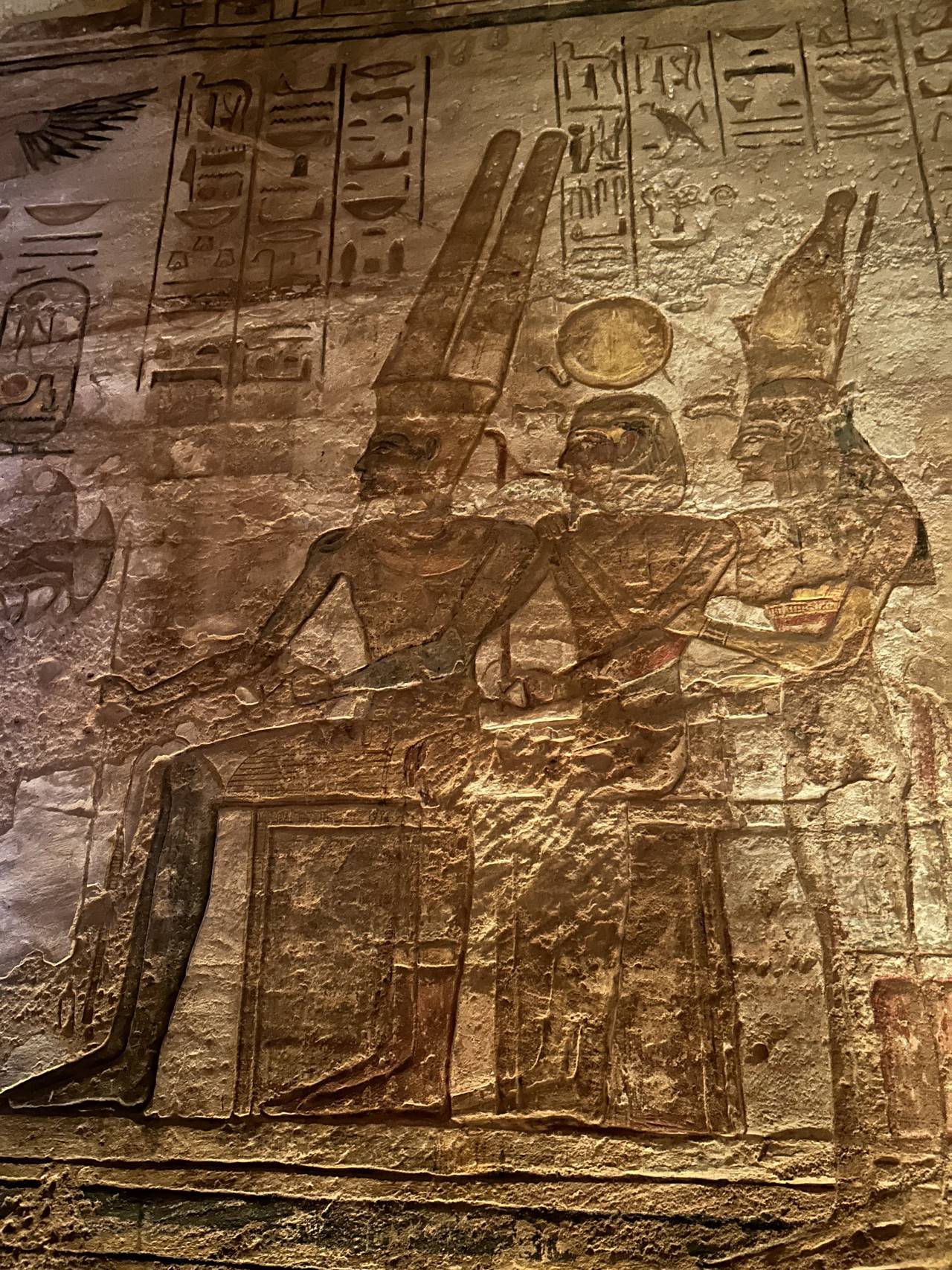 Reliéf egyptských bohů s hieroglyfy na kamenné stěně chrámu
