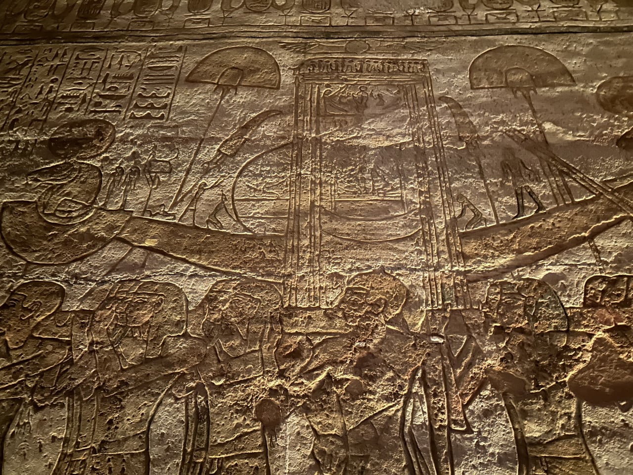 Reliéf egyptských hieroglyfů a vyobrazení na kamenné stěně Abu Simbelu.