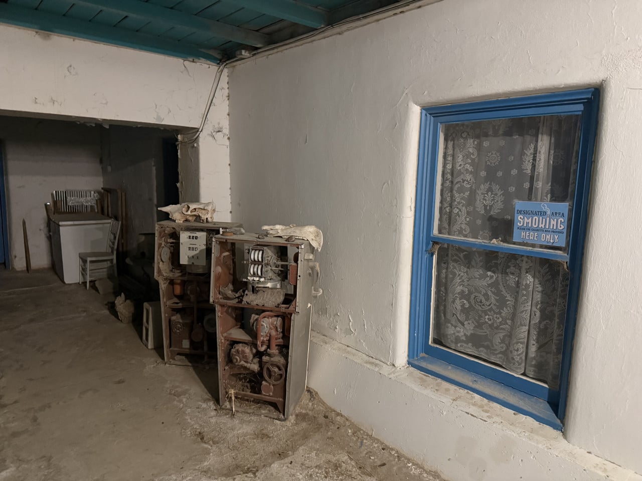 Opotřebovaný interiér hotelu s modrým oknem a cedulí Designated Area Smoking Here Only