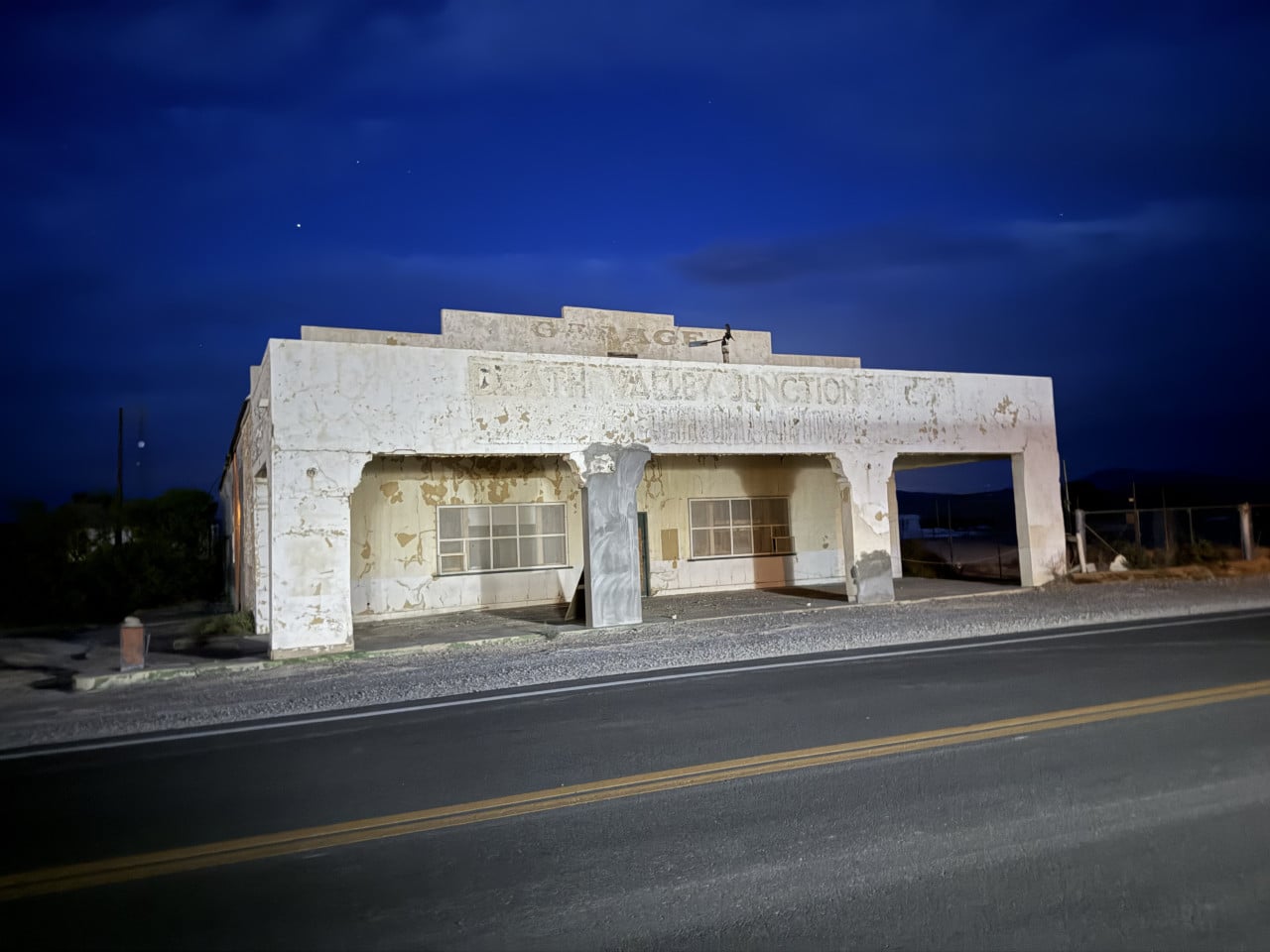 Opotřebovaná budova Amargosa Opera House u silnice v noci pod hvězdnou oblohou