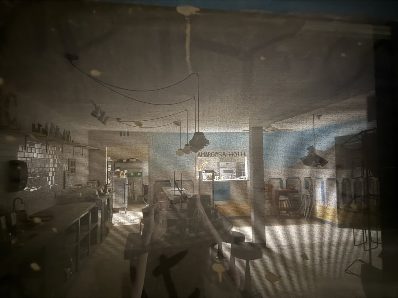 Tmavý interiér hotelu s nápisem AMARGOSA HOTEL a zrcadlovými odrazy.