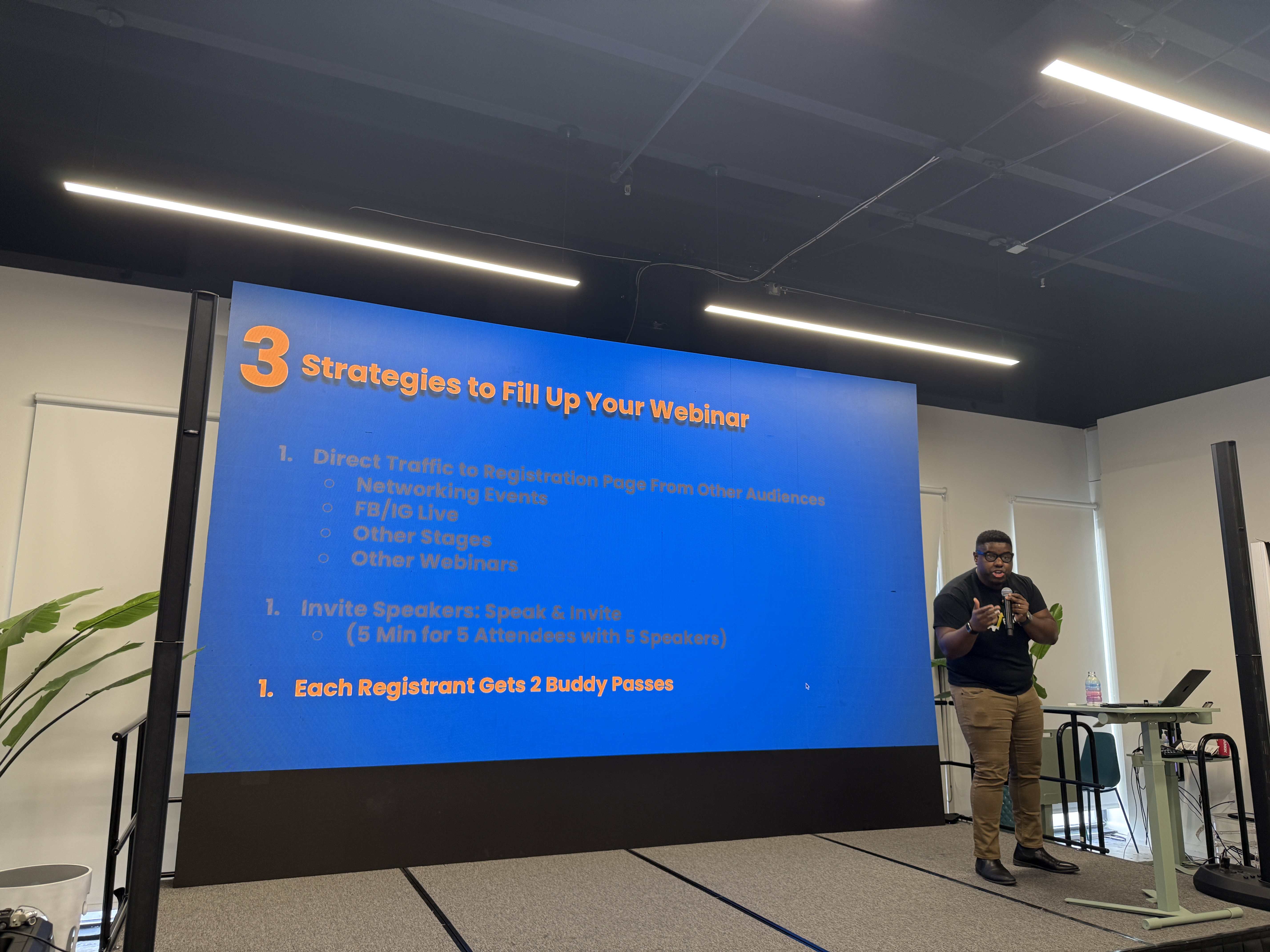 Řečník na pódiu u prezentace 3 Strategies to Fill Up Your Webinar