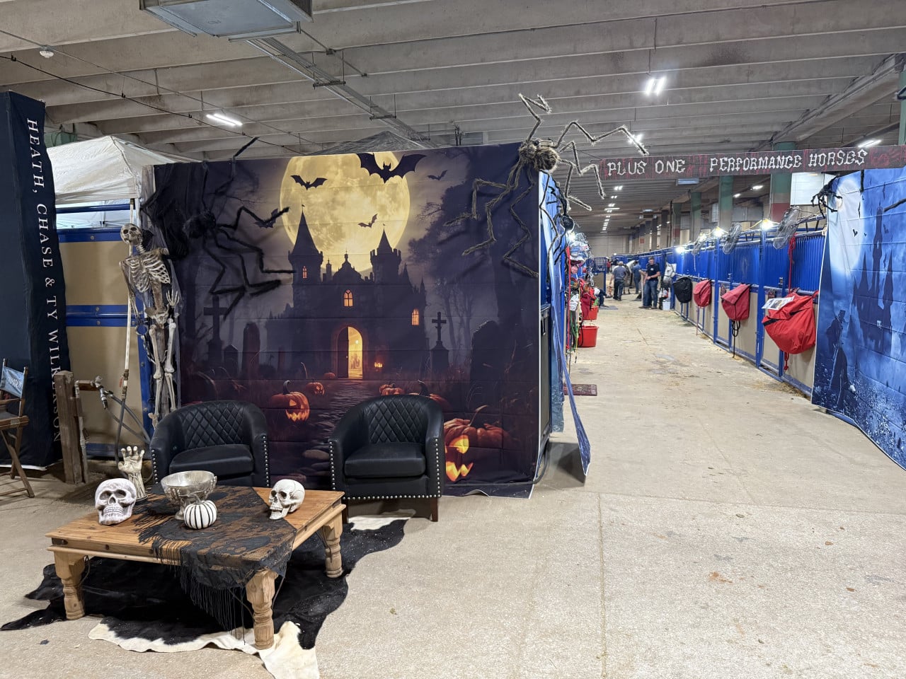 Halloweenský stánek v koňských stájích s kostlivci, dýněmi a měsícem pohrdkou.