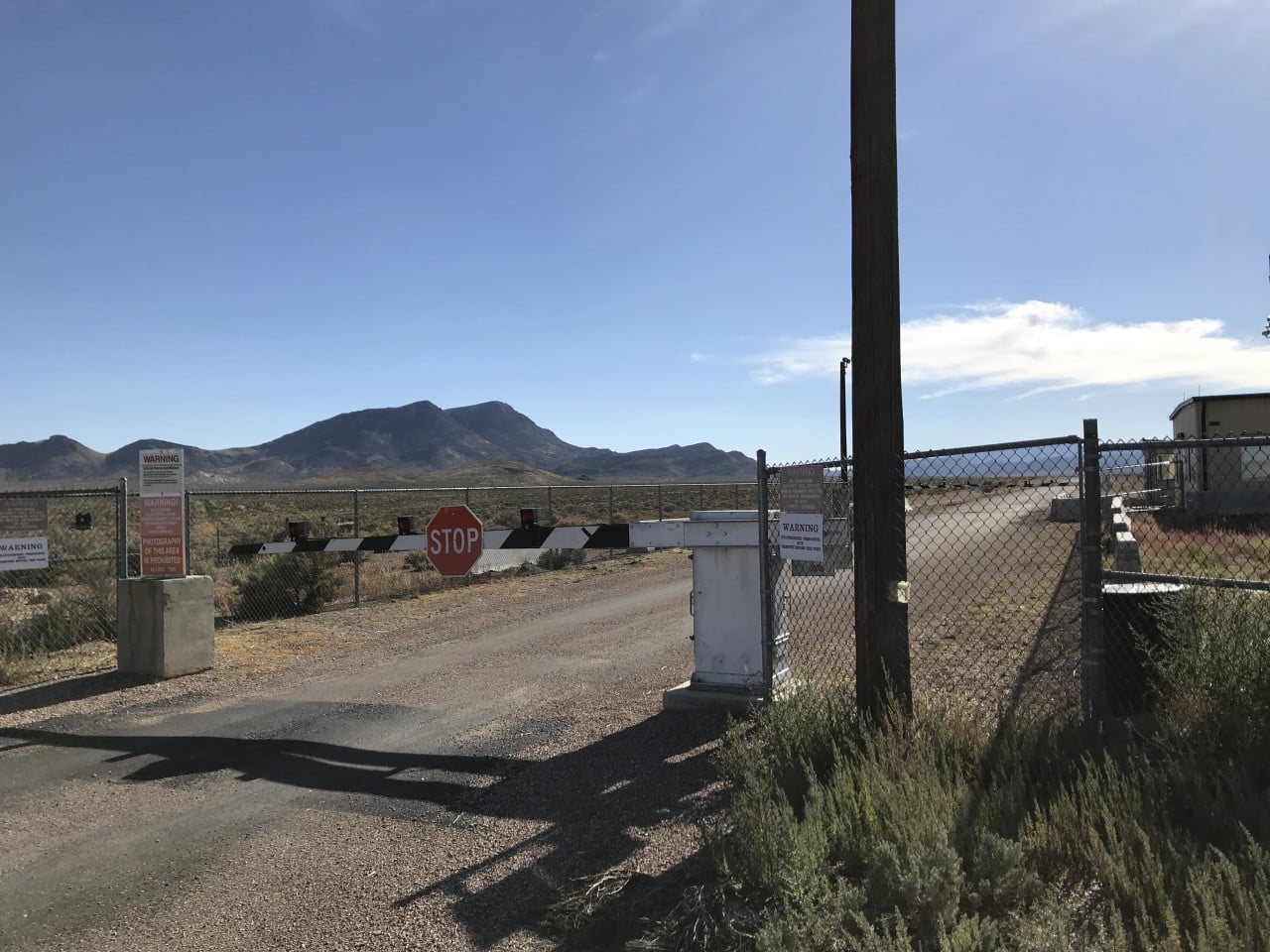 Brána s nápisem STOP a výstražnými cedulemi v poušti u Area 51.