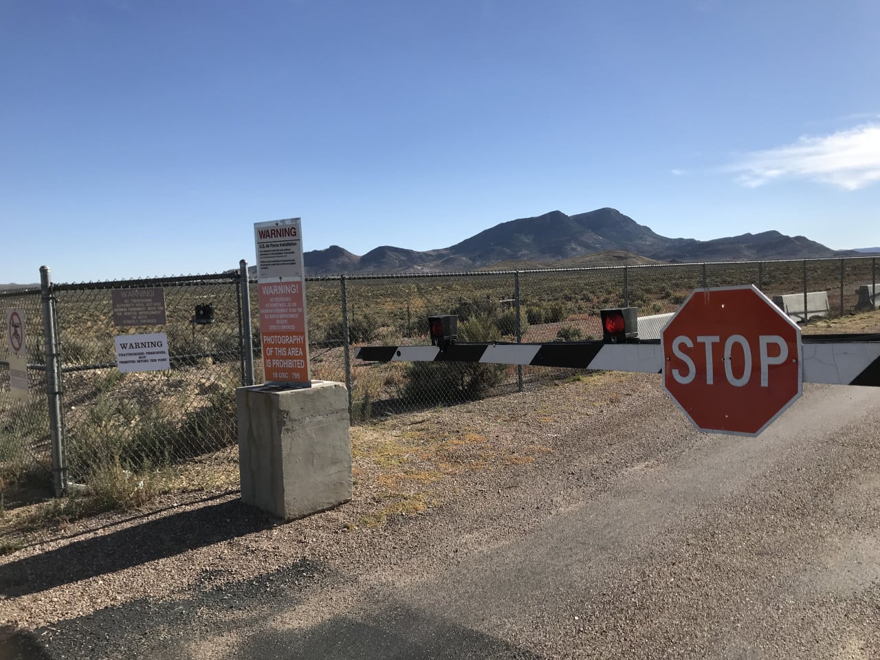 Brána Area 51 s červenou stop značkou a varovnými cedulemi v nevadské poušti