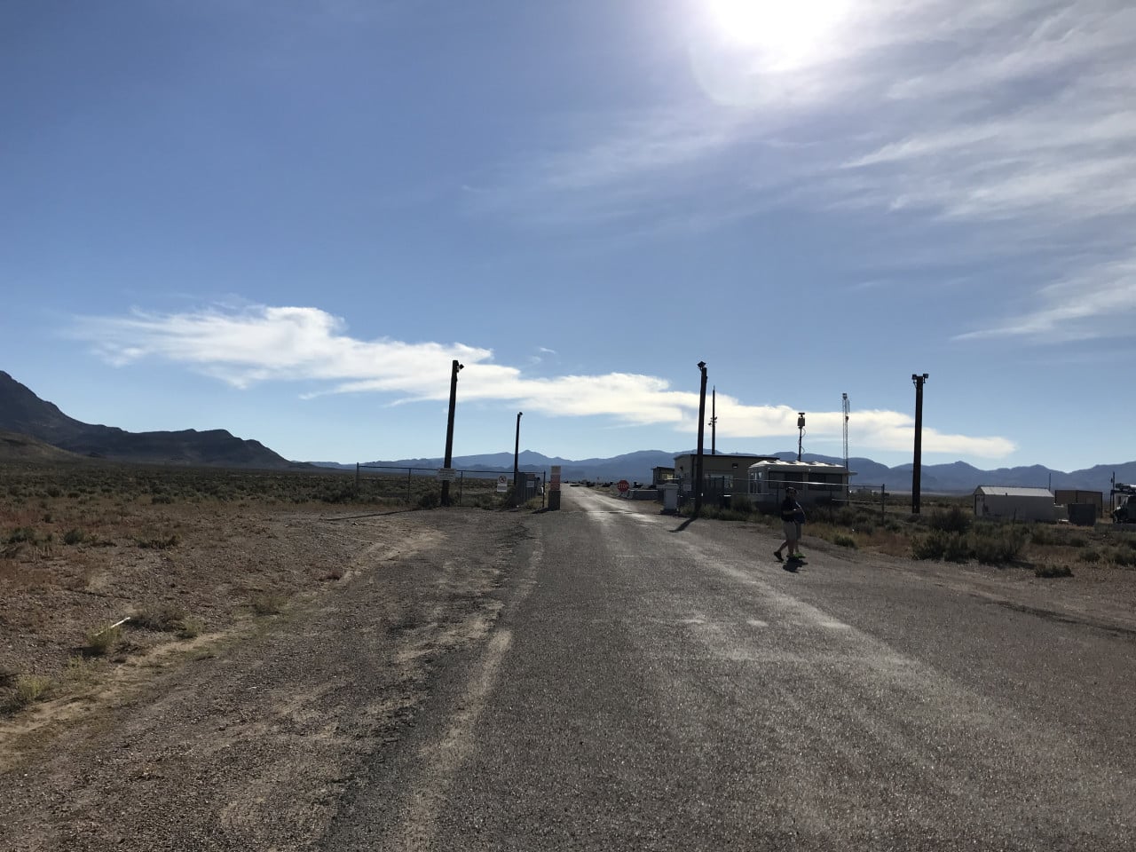 Pouštní silnice k bráně Area 51, strážní stanoviště a hory v dálce