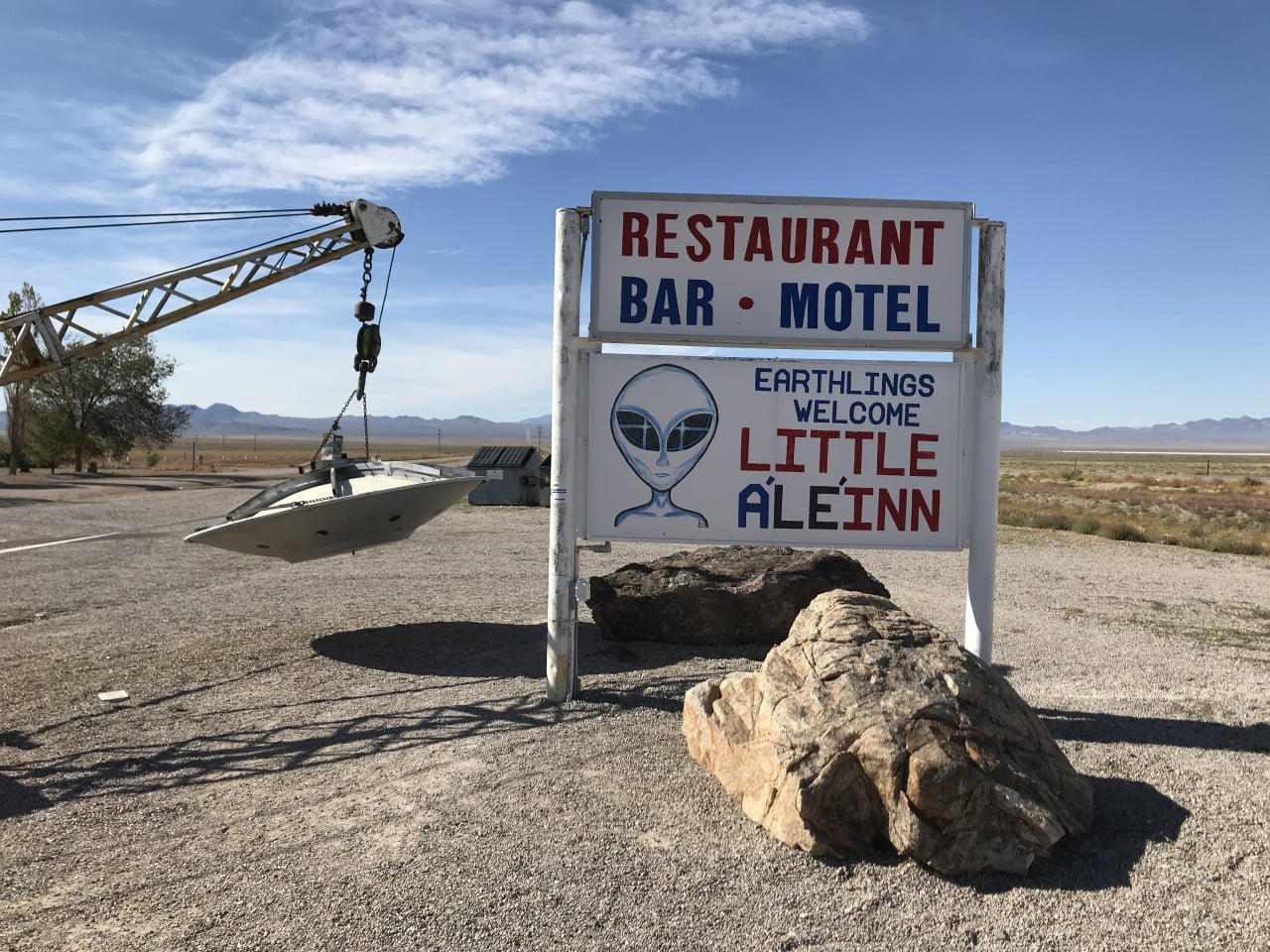 Pouštní cedule Little A’Le’Inn s nápisem Restaurant, Bar, Motel a obrázkem mimozemšťana.