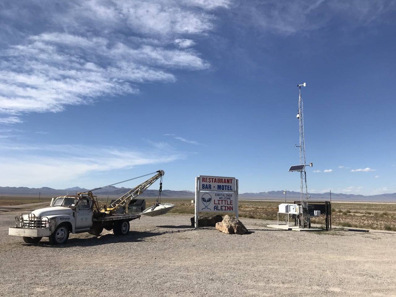 Pouštní motel Little A’Le’Inn u Rachel s nápisem Restaurant Bar Motel a starým odtahovým autem.