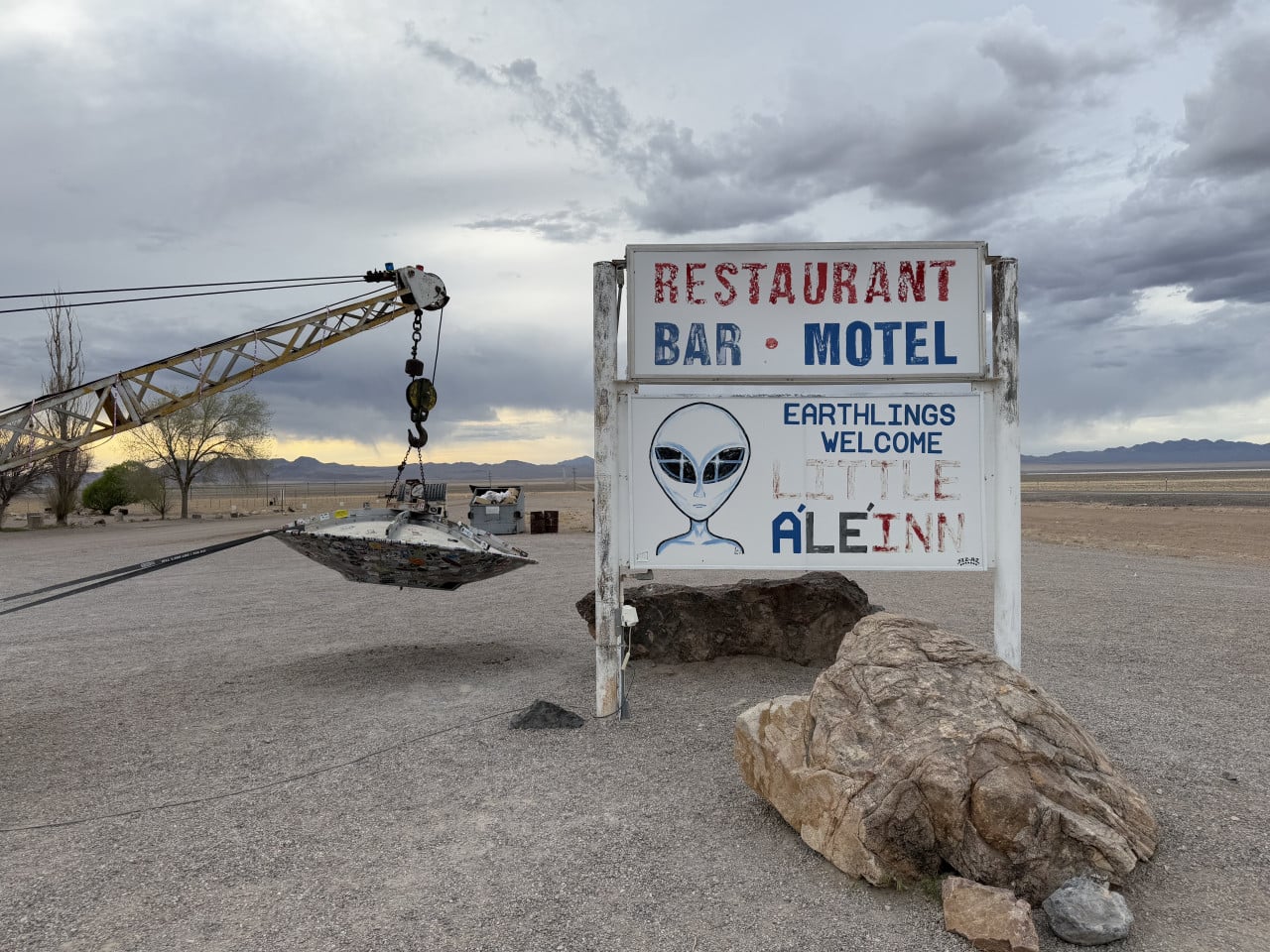 Cedule Little A’Le’Inn s textem Earthlings Welcome a UFO jeřáb v poušti Rachel, Nevada