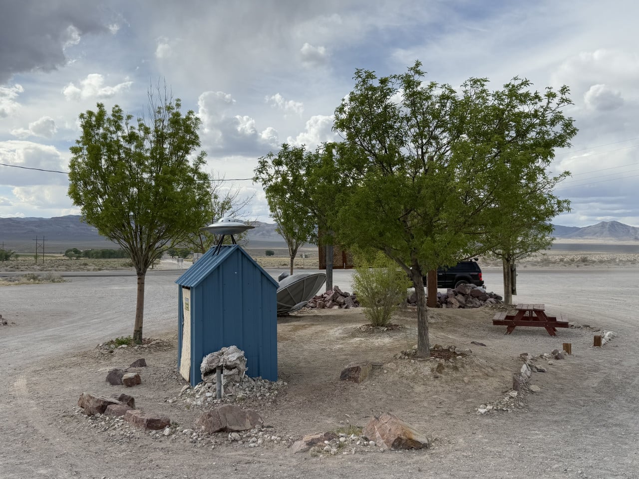 Modrá bouda s modelem UFO u stromů v pouštní krajině Nevady