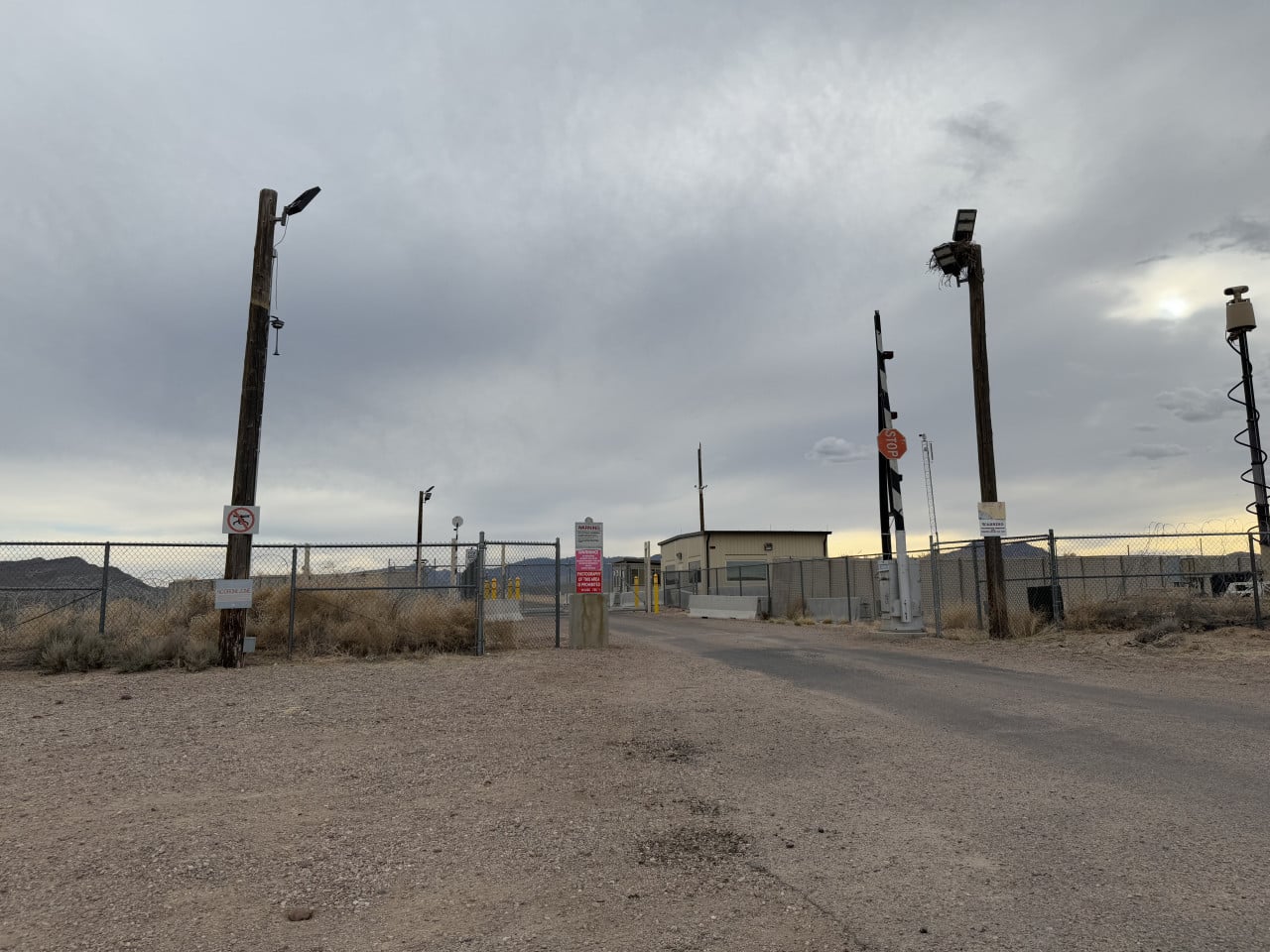 Vstupní brána k Area 51 s plotem, stopkou a varovnými cedulemi v poušti