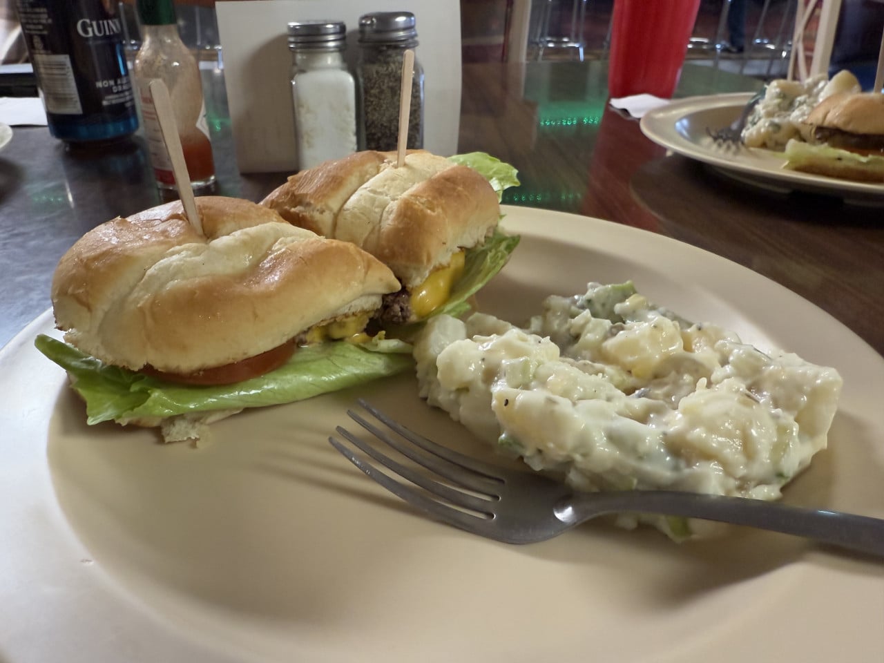 Dva cheeseburgery s bramborovým salátem na talíři v restauraci.