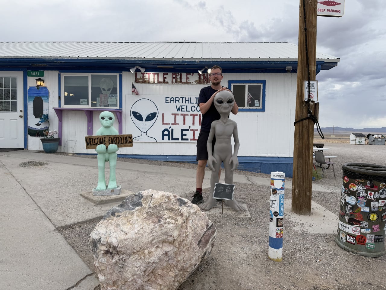 Muž pózuje u soch mimozemšťanů před Little A'Le'Inn v Rachel, Nevada.
