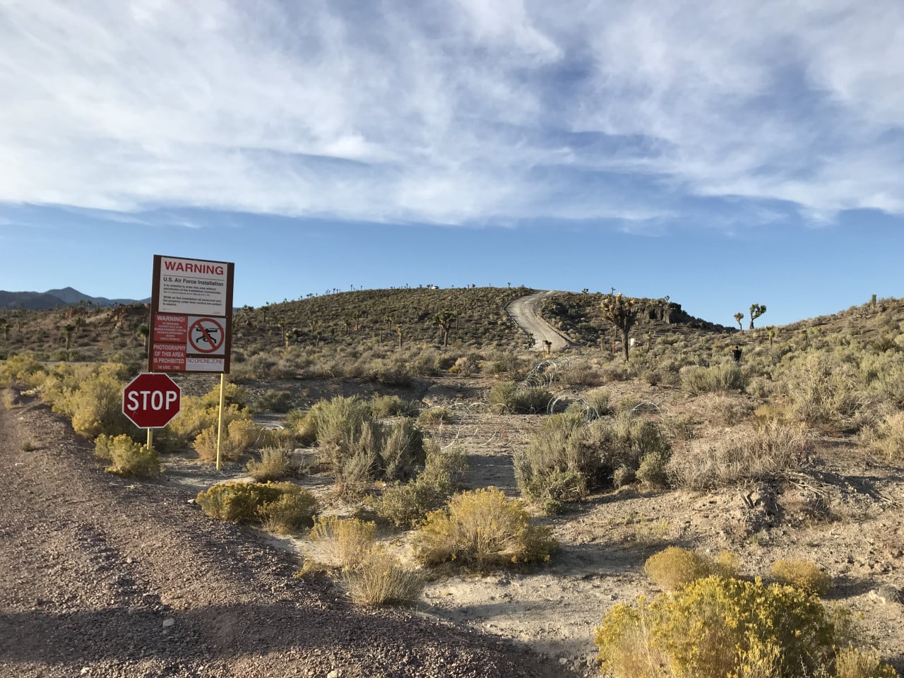 Vstupní brána Area 51 s výstražnými cedulemi a stopkou v nevadské poušti