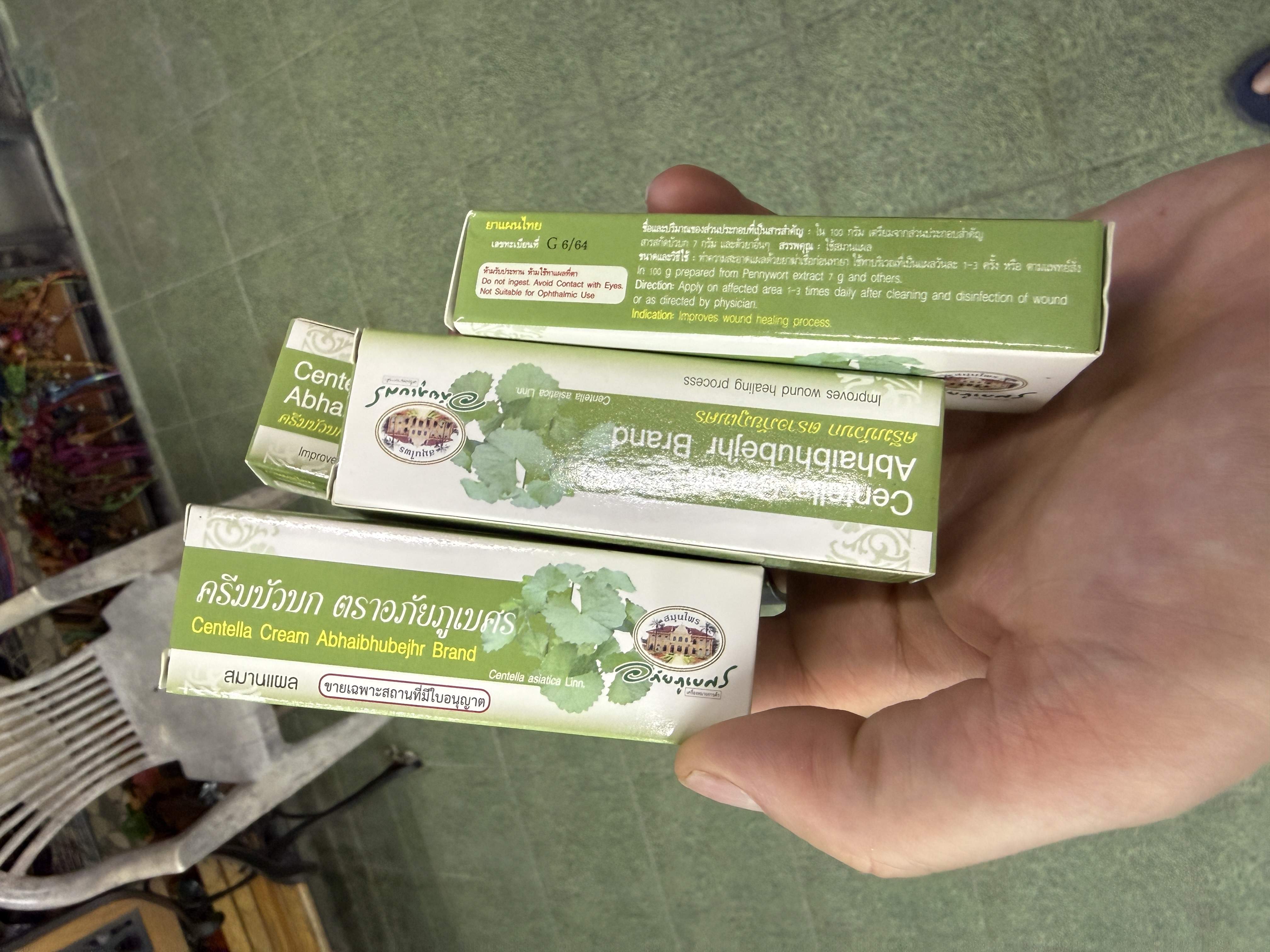 Ruka drží krabičky masti Centella Abhaibhubejhr Brand, text Improves wound healing process