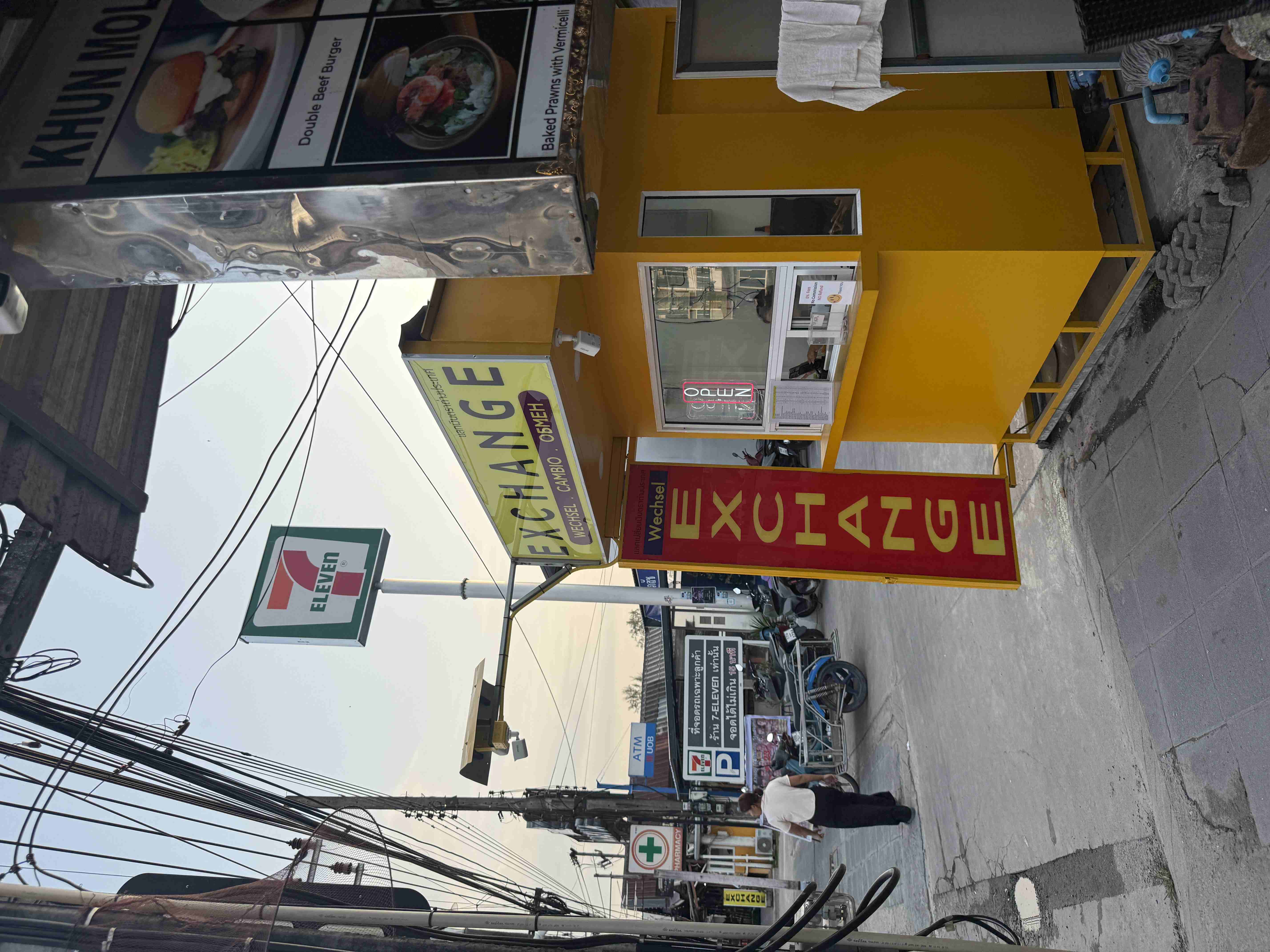 Žlutá směnárna s nápisy EXCHANGE a OPEN vedle cedule 7-ELEVEN.