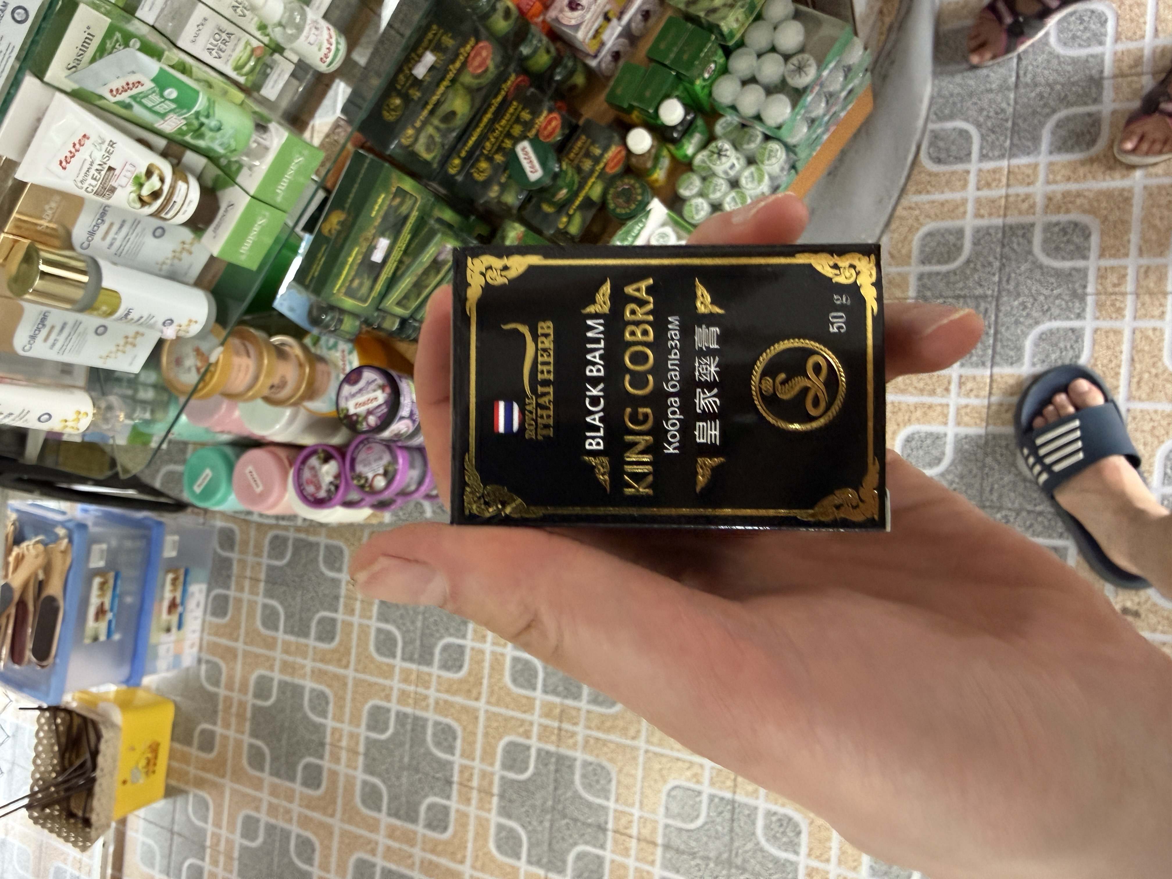 Ruka drží krabičku Royal Thai Herb Black Balm King Cobra 50 g