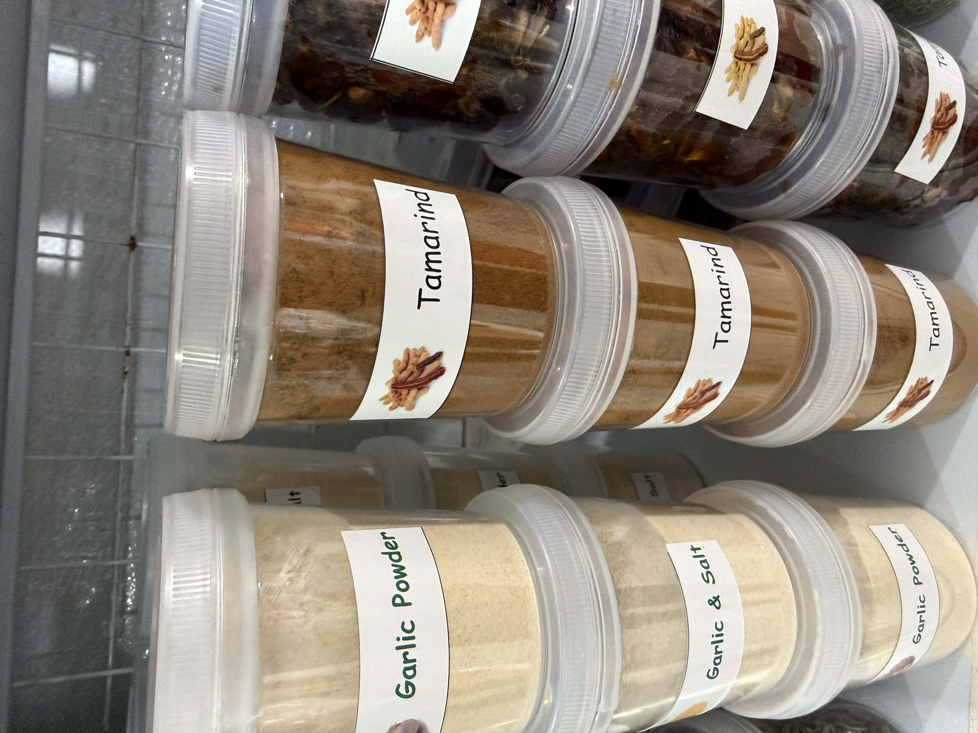 Plastové dózy s kořením, popisky Garlic Powder, Garlic & Salt a Tamarind.