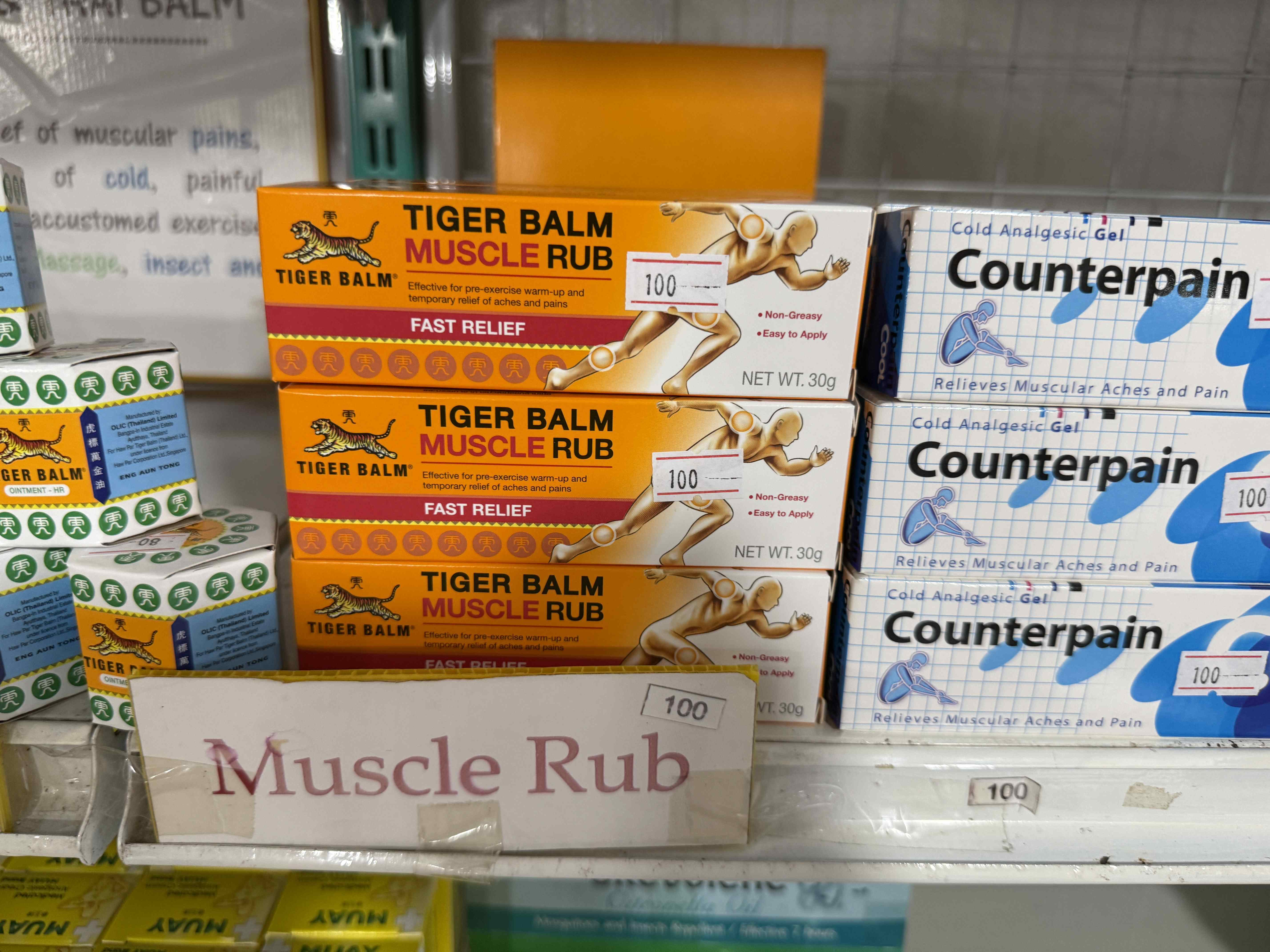Krabičky TIGER BALM MUSCLE RUB a Counterpain, cenovky 100, cedule Muscle Rub.