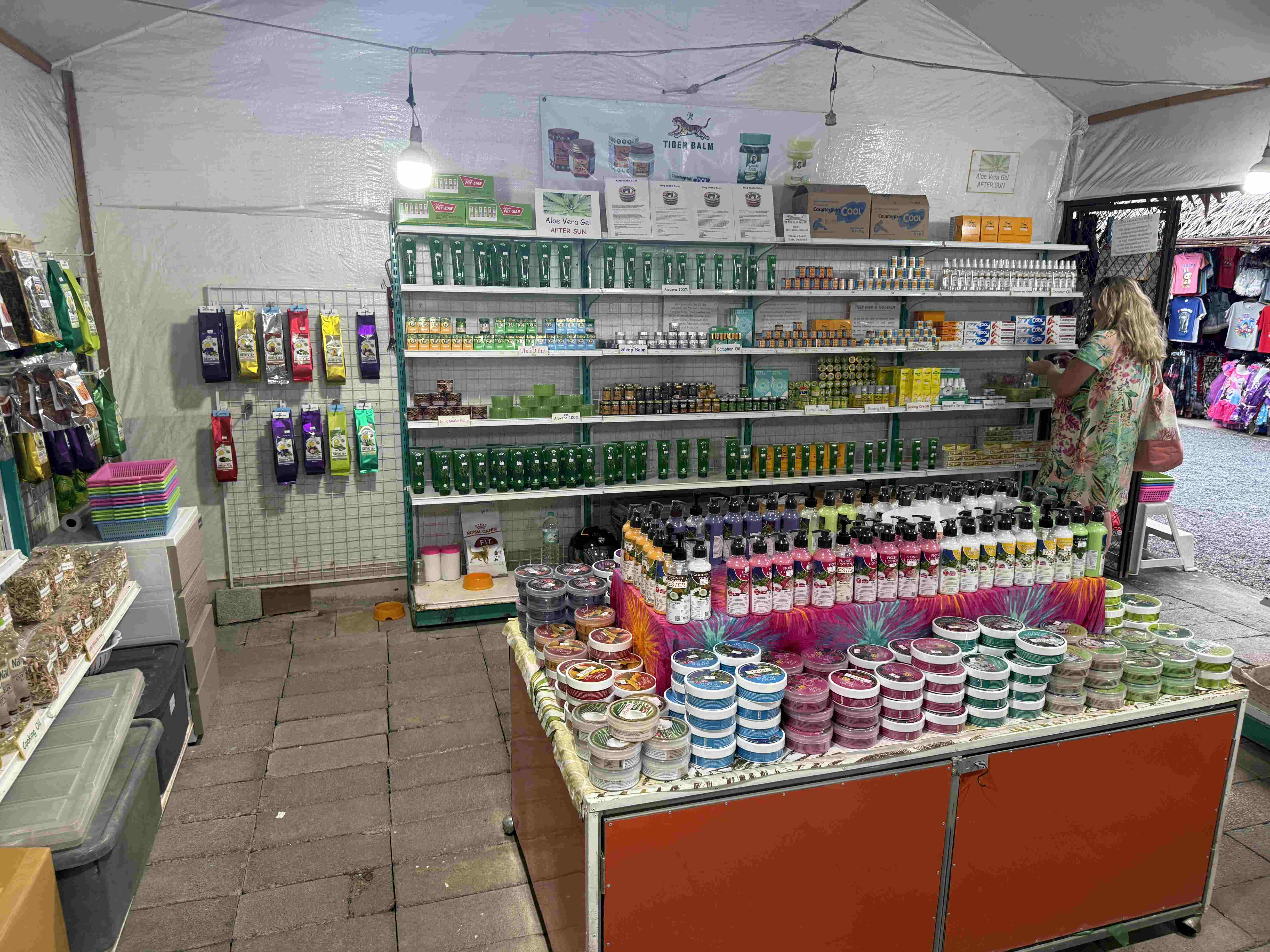 Stánek na trhu s mastmi, nápisy TIGER BALM a Aloe Vera Gel AFTER SUN.