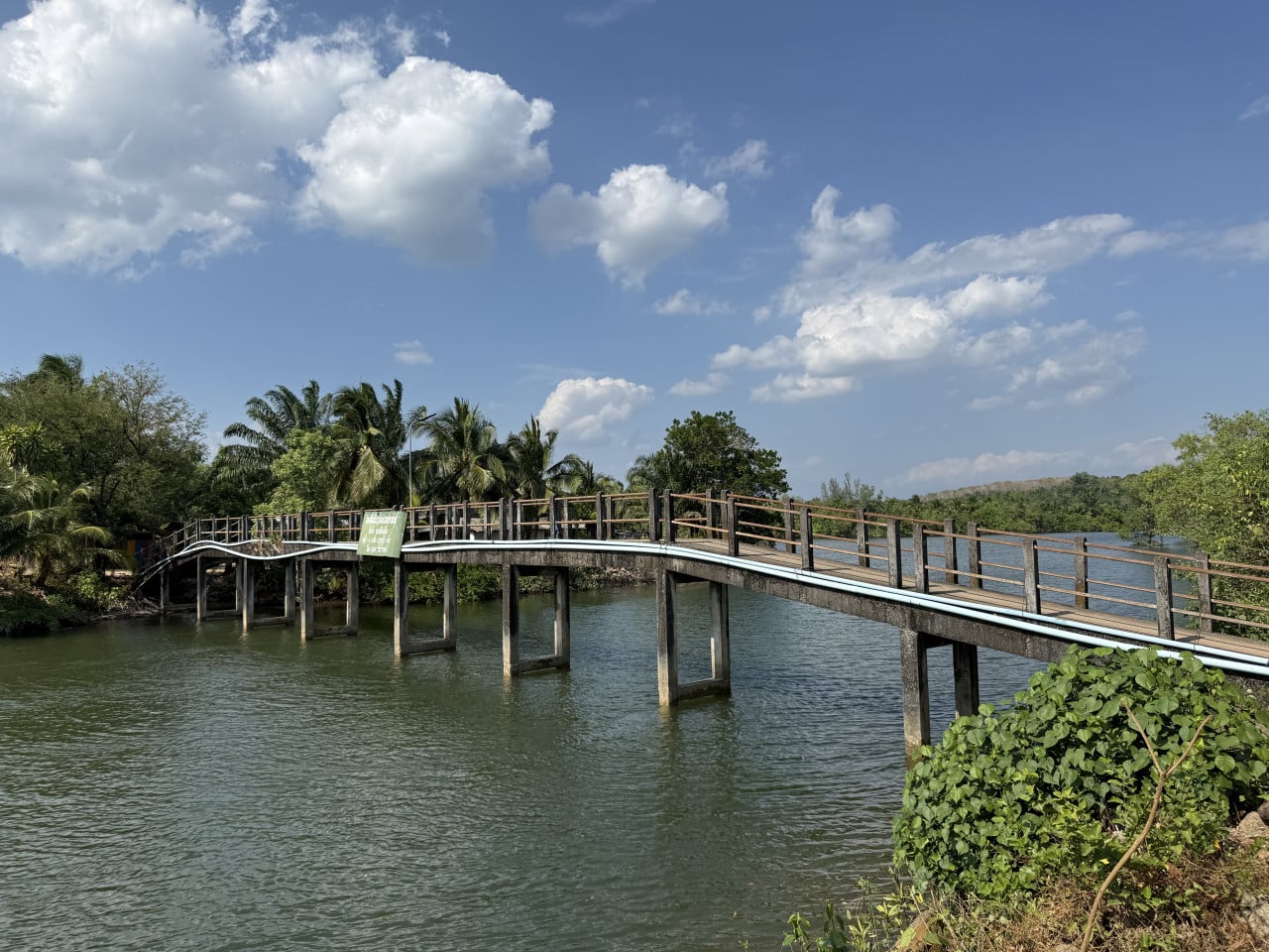 Dřevěný most přes řeku v Bang Wan, palmy a modré nebe