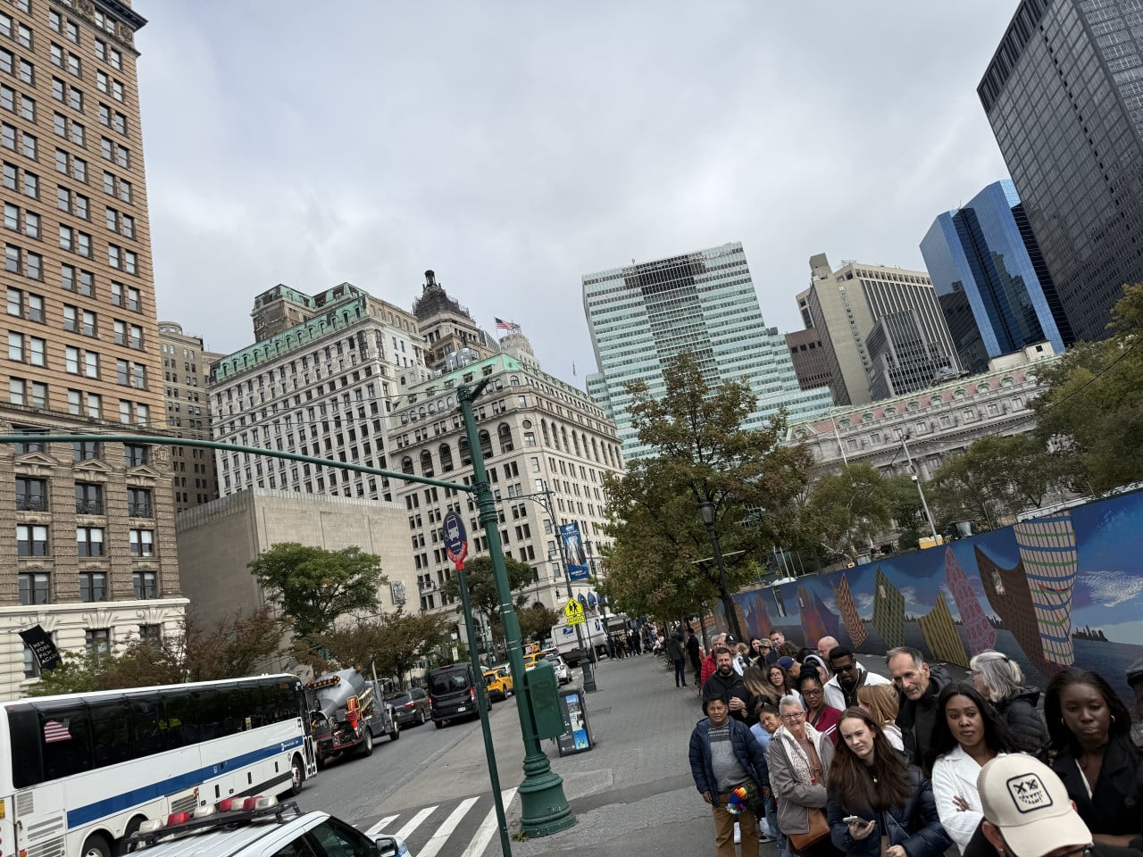 Rušná ulice v Battery Parku s turisty, autobusem a mrakodrapy New Yorku.