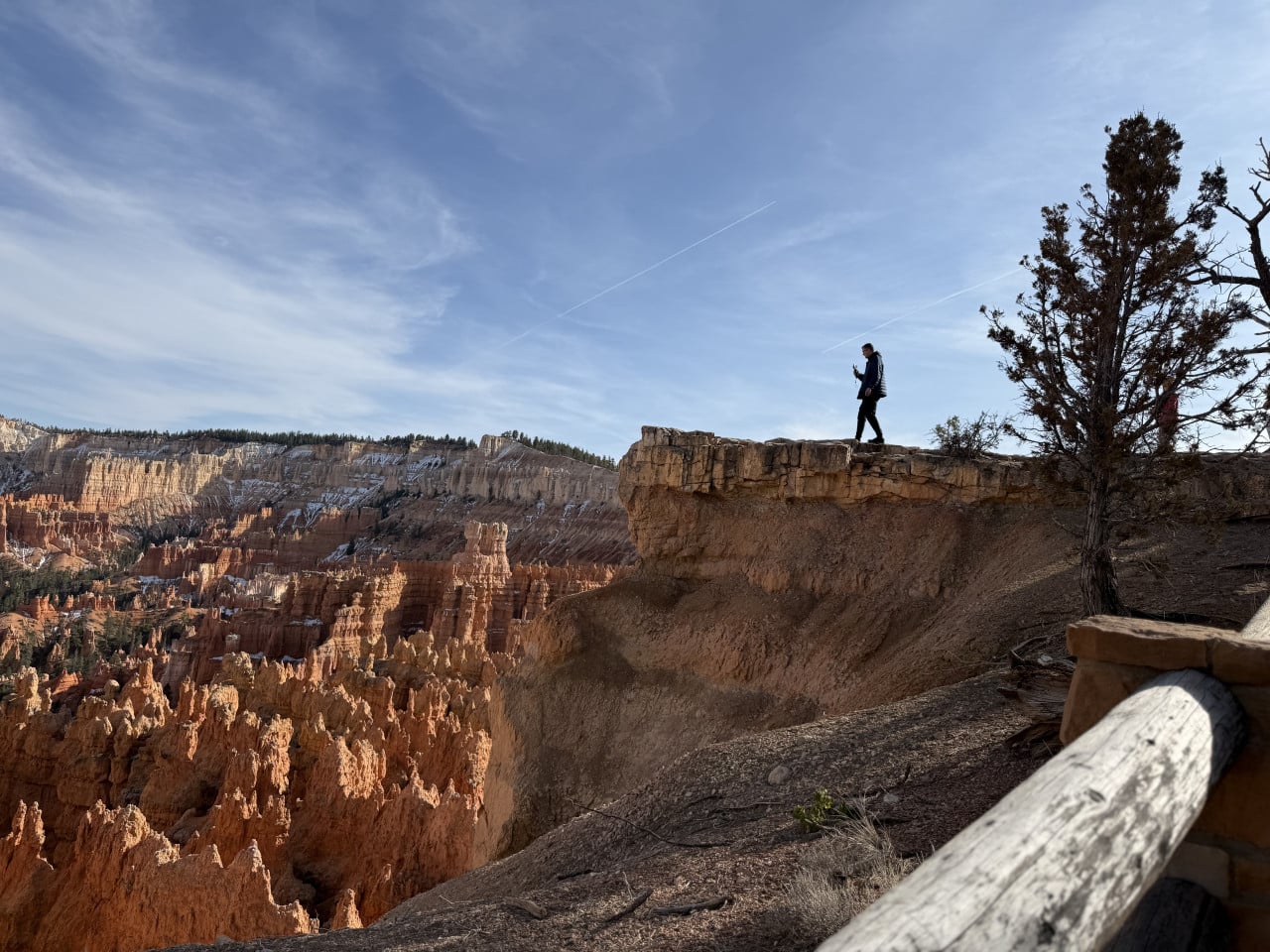 Postava na okraji útesu nad oranžovými skalními věžemi Bryce Canyonu.