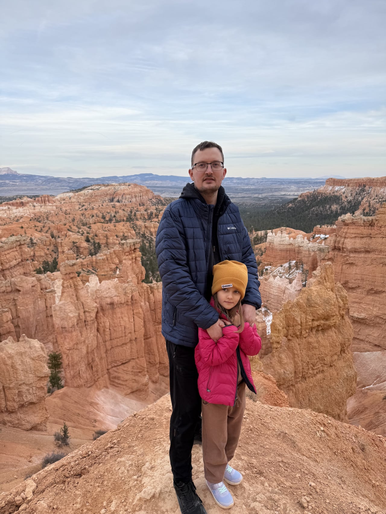 Muž s dívkou v růžové bundě na vyhlídce Bryce Canyon, nápis SHOOEY