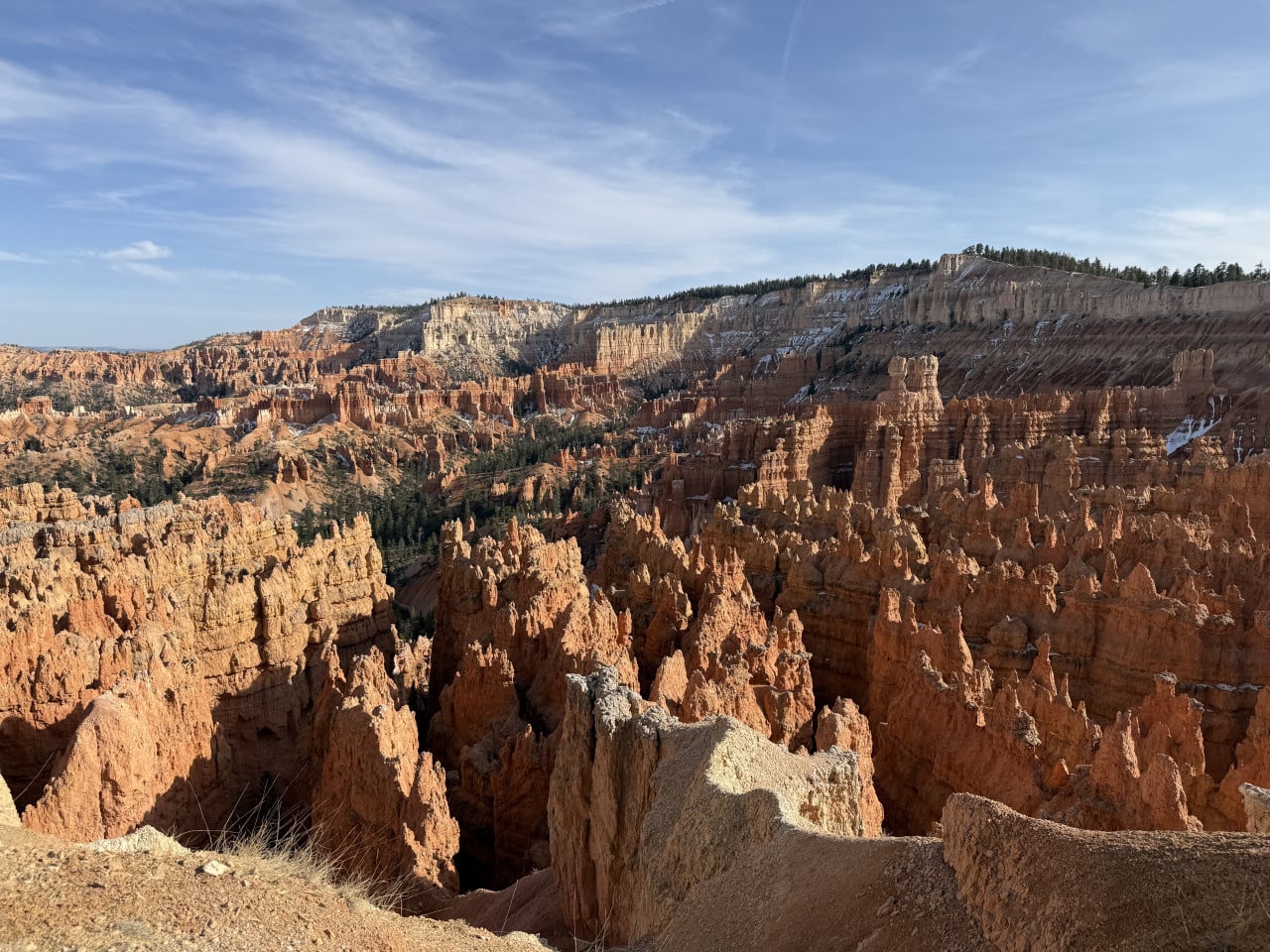 Panorama Bryce Canyonu: oranžové skalní věže hoodoo, útesy se sněhem a modrá obloha