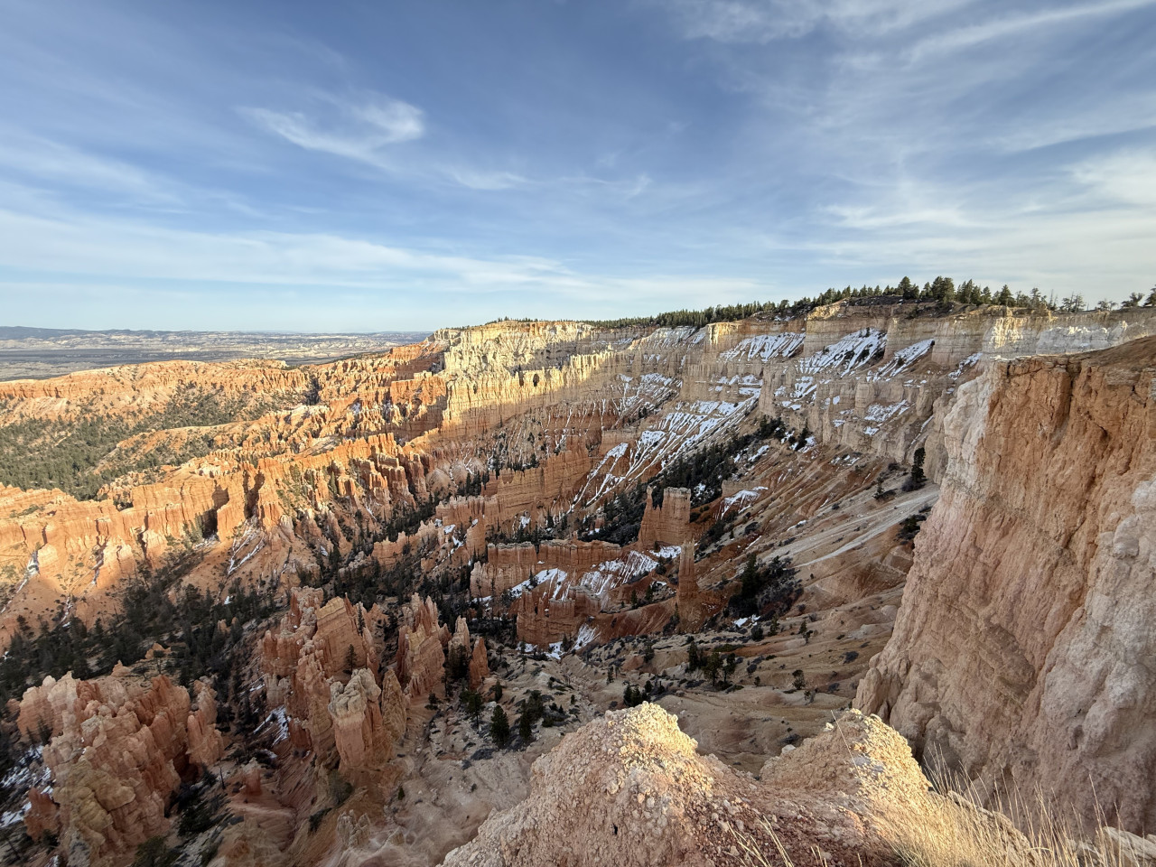 Panorama Bryce Canyonu s oranžovými hoodoos, skalními stěnami a zbytky sněhu