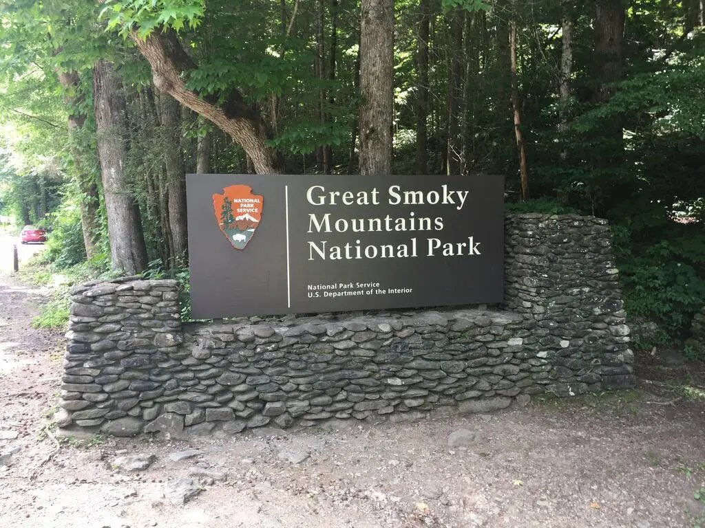 Vstupní cedule Great Smoky Mountains National Park na kamenné zídce u lesa